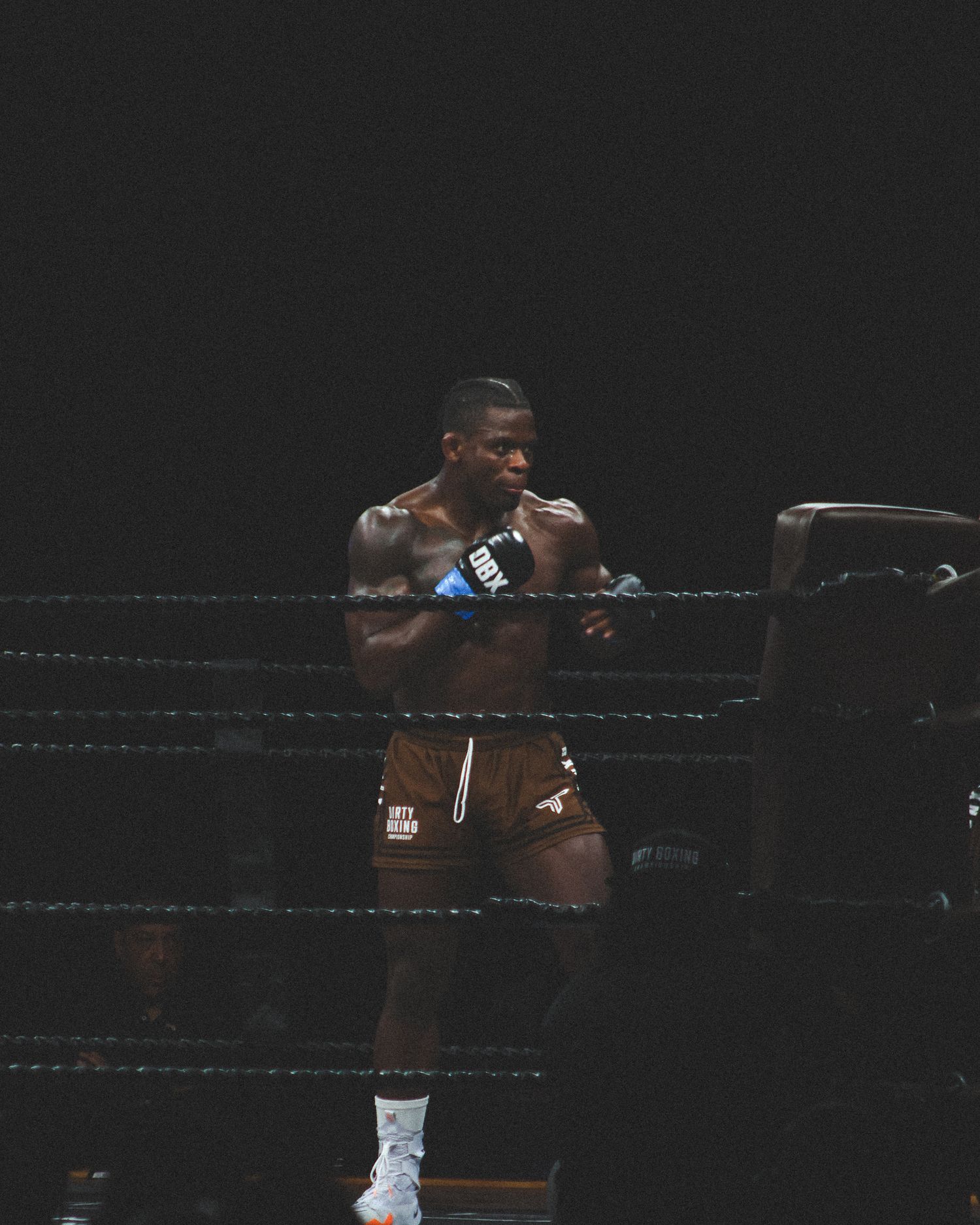 Two athletes trade punches during a dramatic boxing match in dark lighting.
