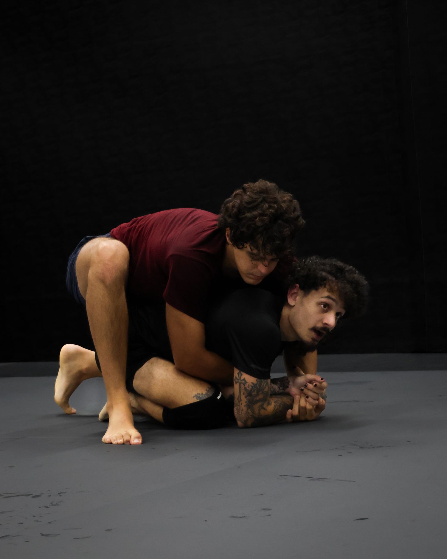 Martial artist demonstrates ground movement technique on dark floor.