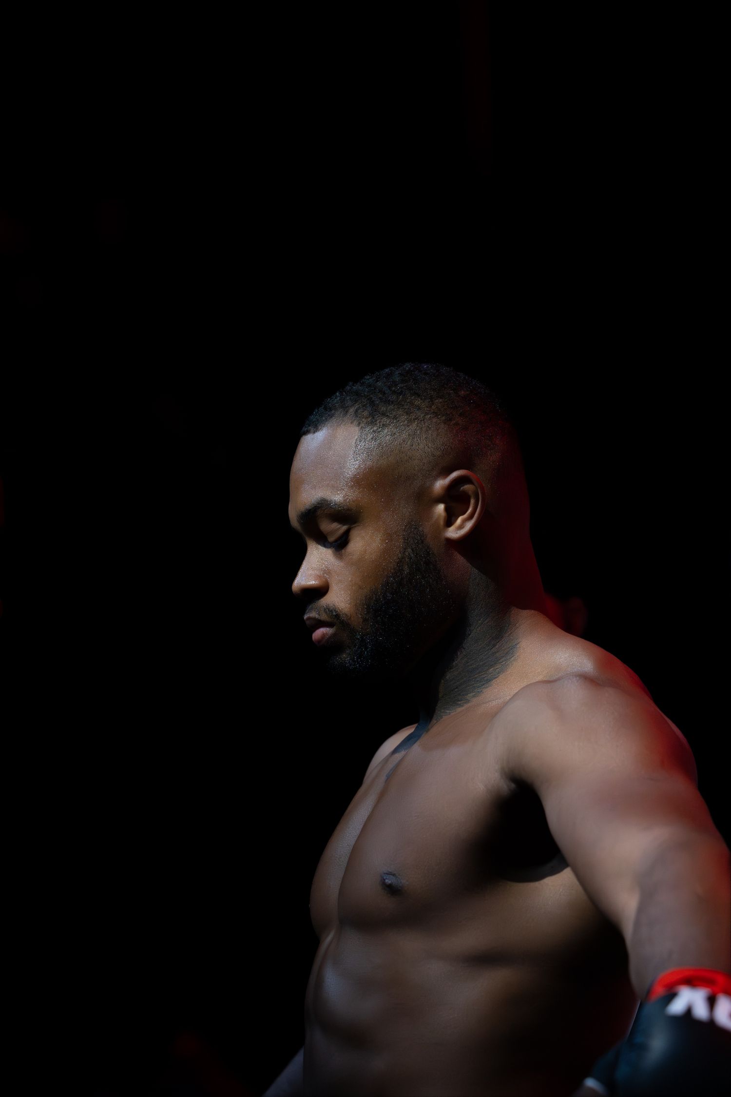 A dramatic side profile shot of a boxer in low light with red accent lighting.