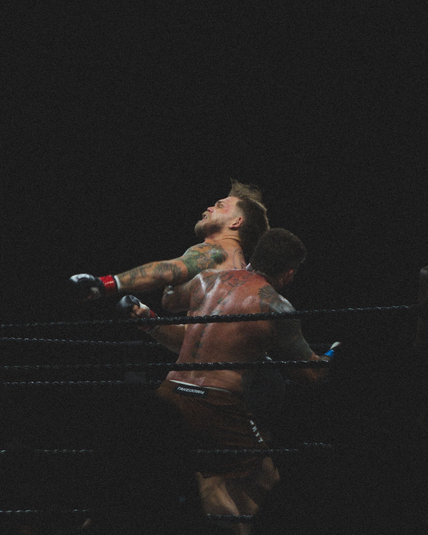 A boxer falls backwards after taking a powerful hit during the match.