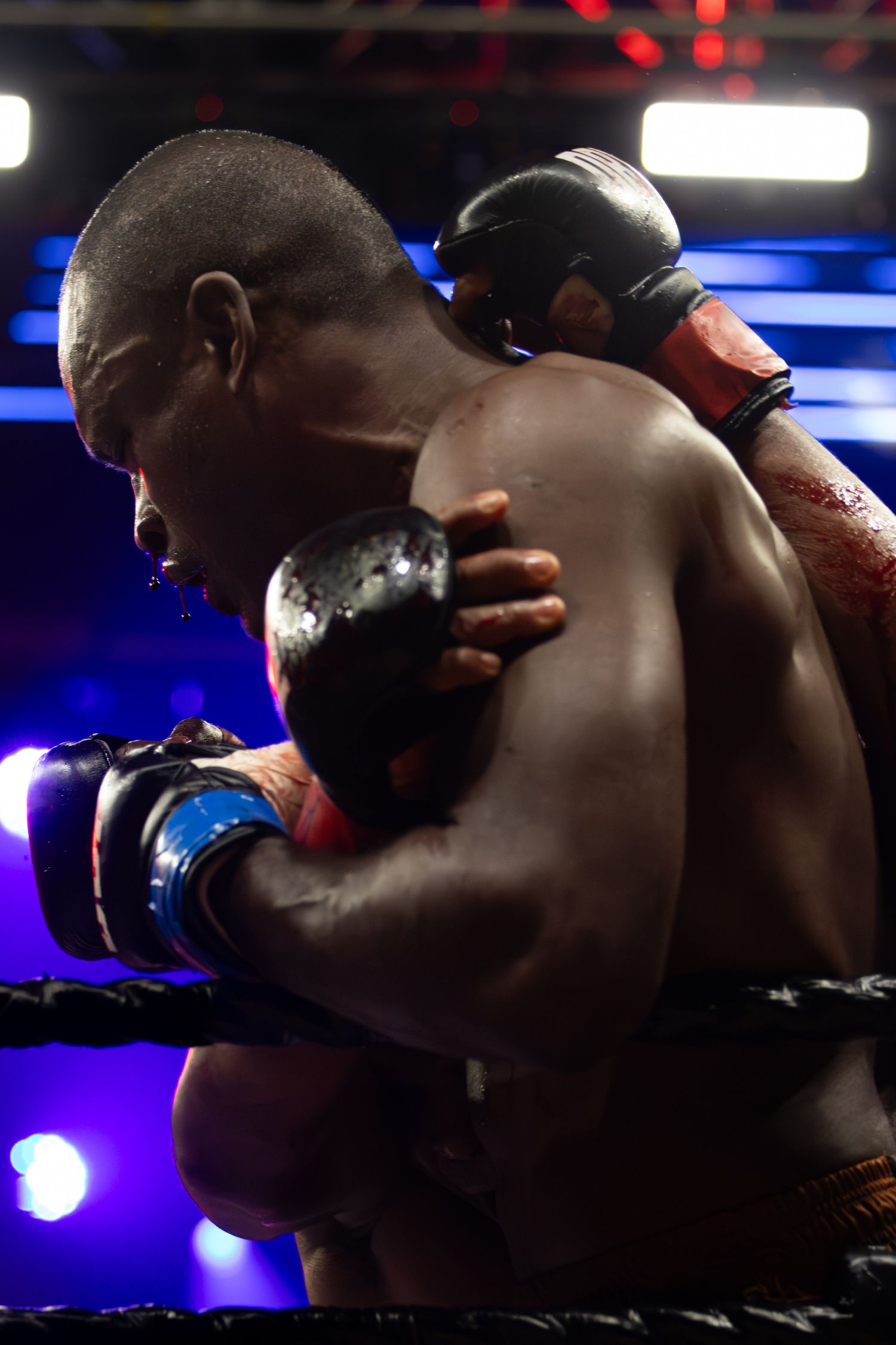 A boxer throws punches during a match with blue and red lighting effects.