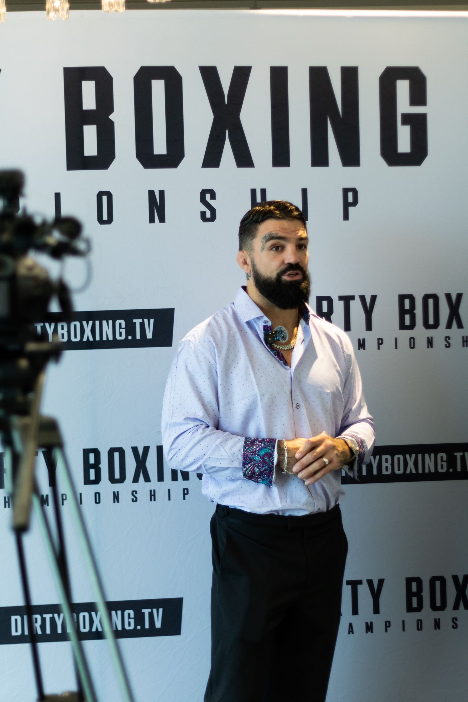 Press conference setup with Dirty Boxing branding and camera equipment visible.