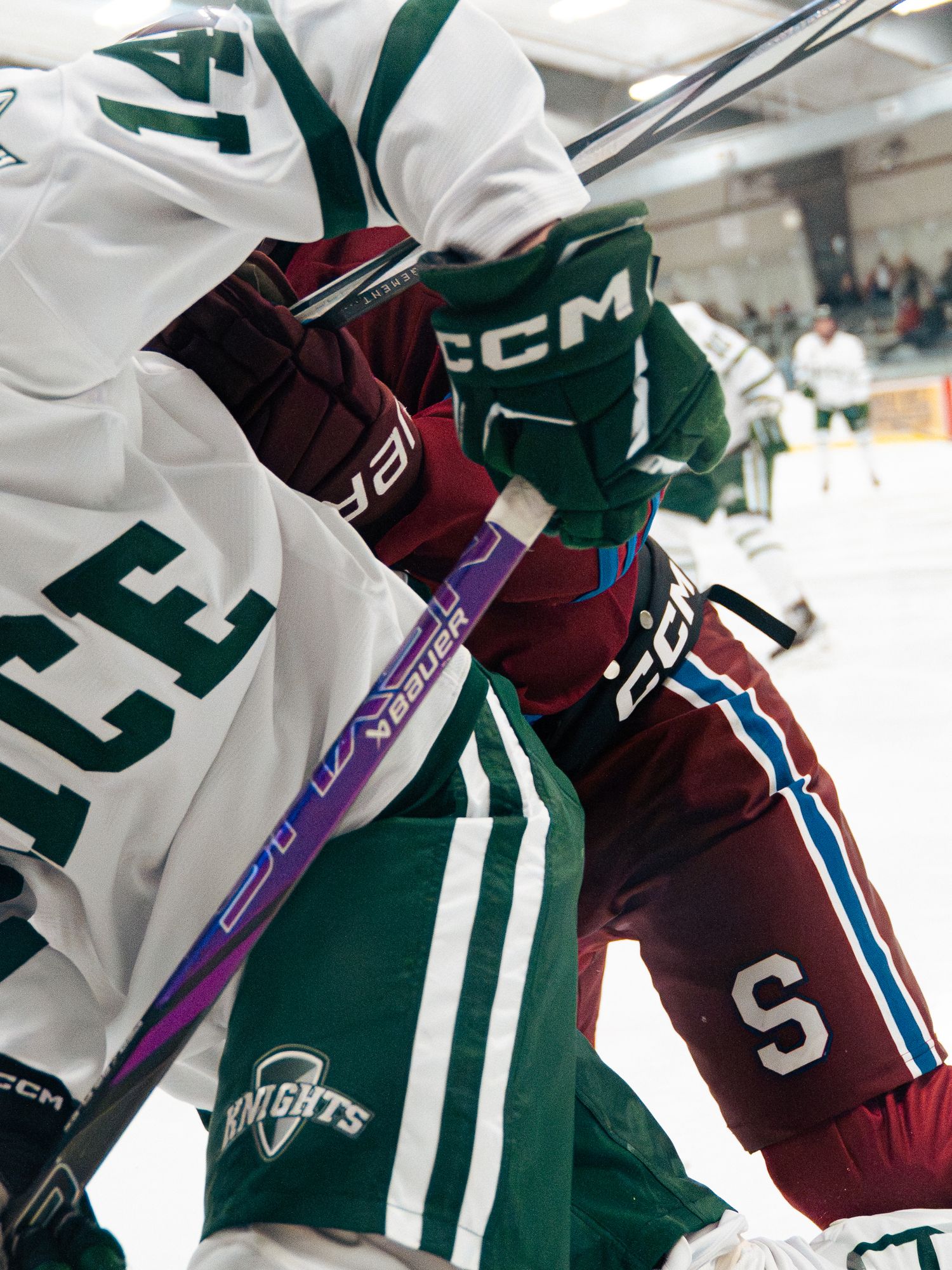 Close-up detail of white and green hockey jerseys with numbers hanging in a row.