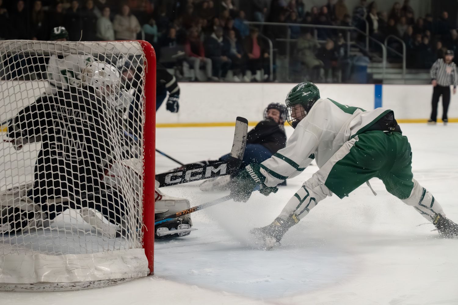Hockey players diving and sliding near goal net during intense game action.
