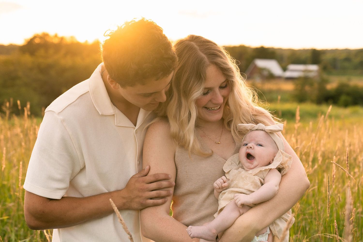 Family sharing tender moments together in a golden sunset field.