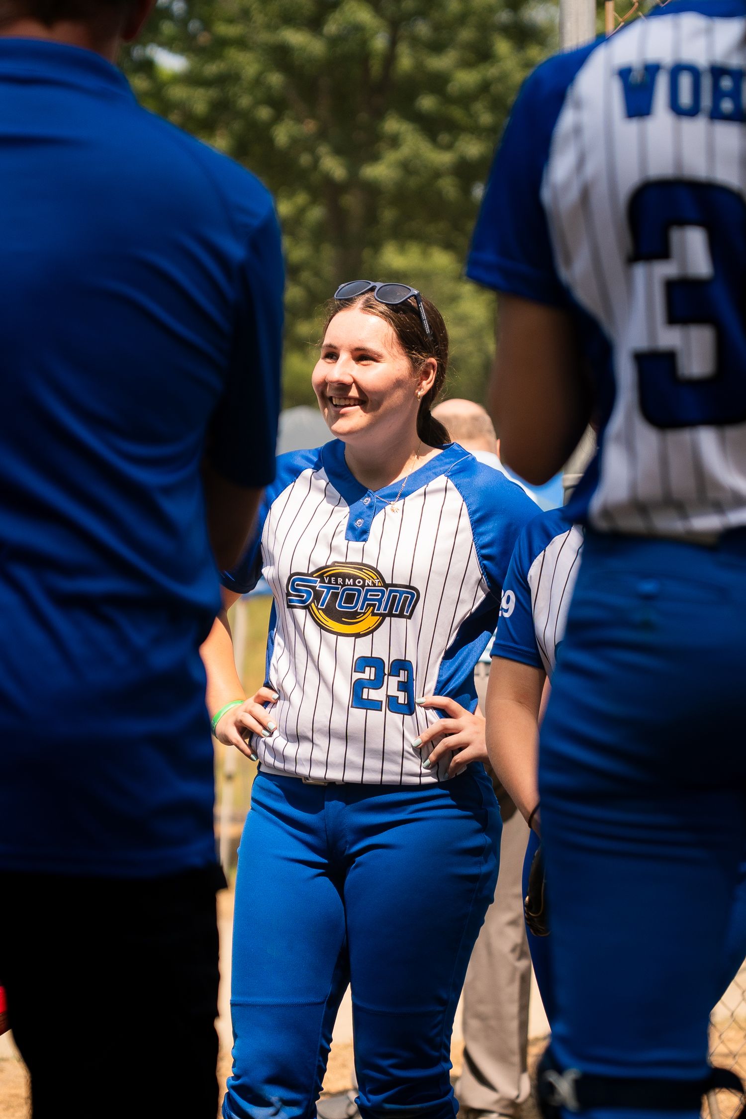 Softball team players in blue and white uniforms gathered on field during game.