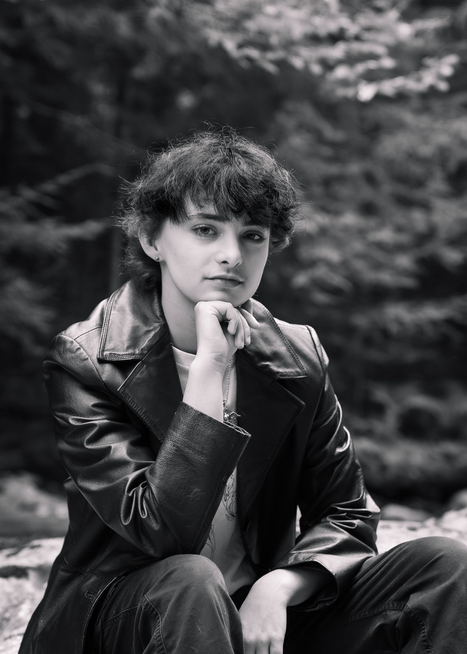 Black and white artistic portrait series showing a person in dark clothing against a blurred natural background.