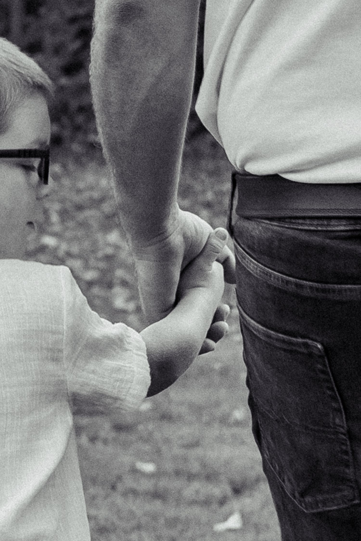 Black and white image showing hands holding each other in a close embrace against a blurred background.