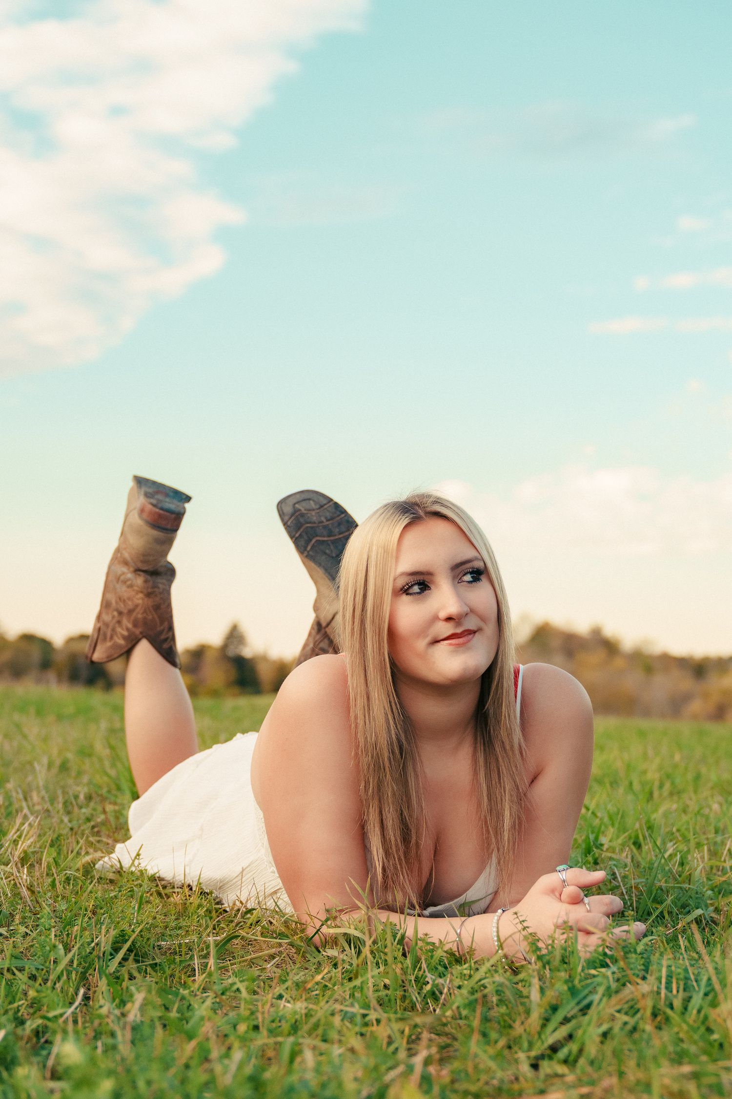 Person relaxing on green grass in brown boots during a sunny autumn day.