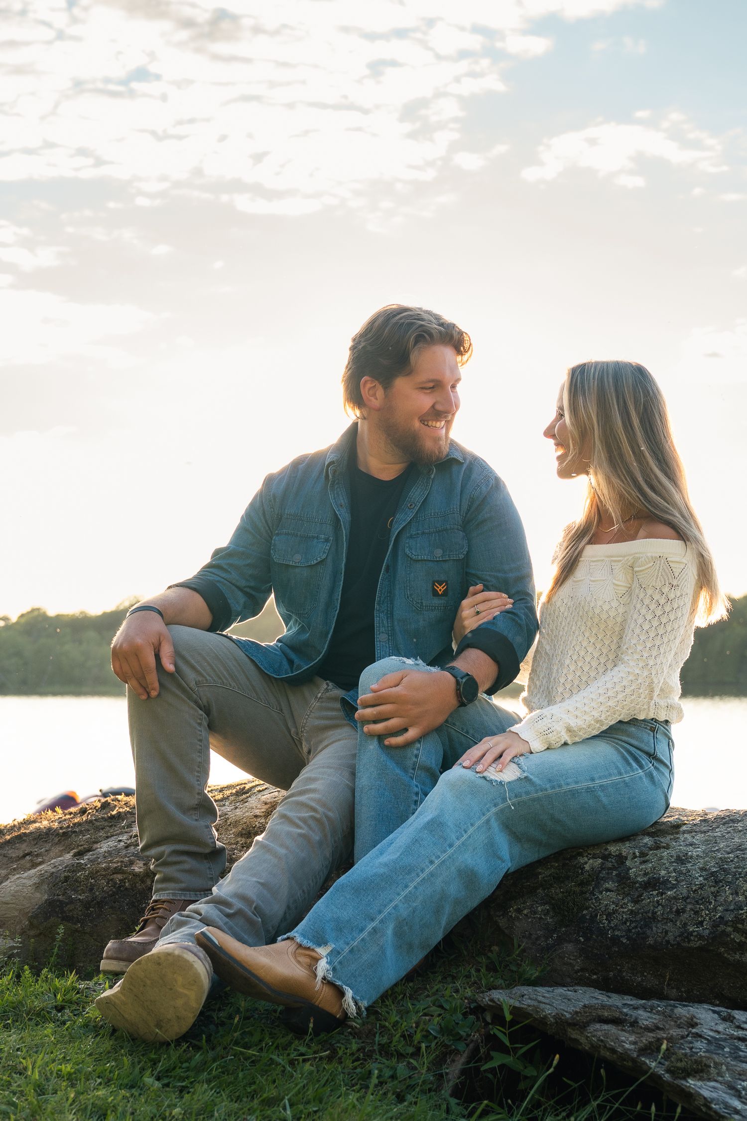Couple in casual attire sitting on rocks at sunset sharing intimate moments in nature.