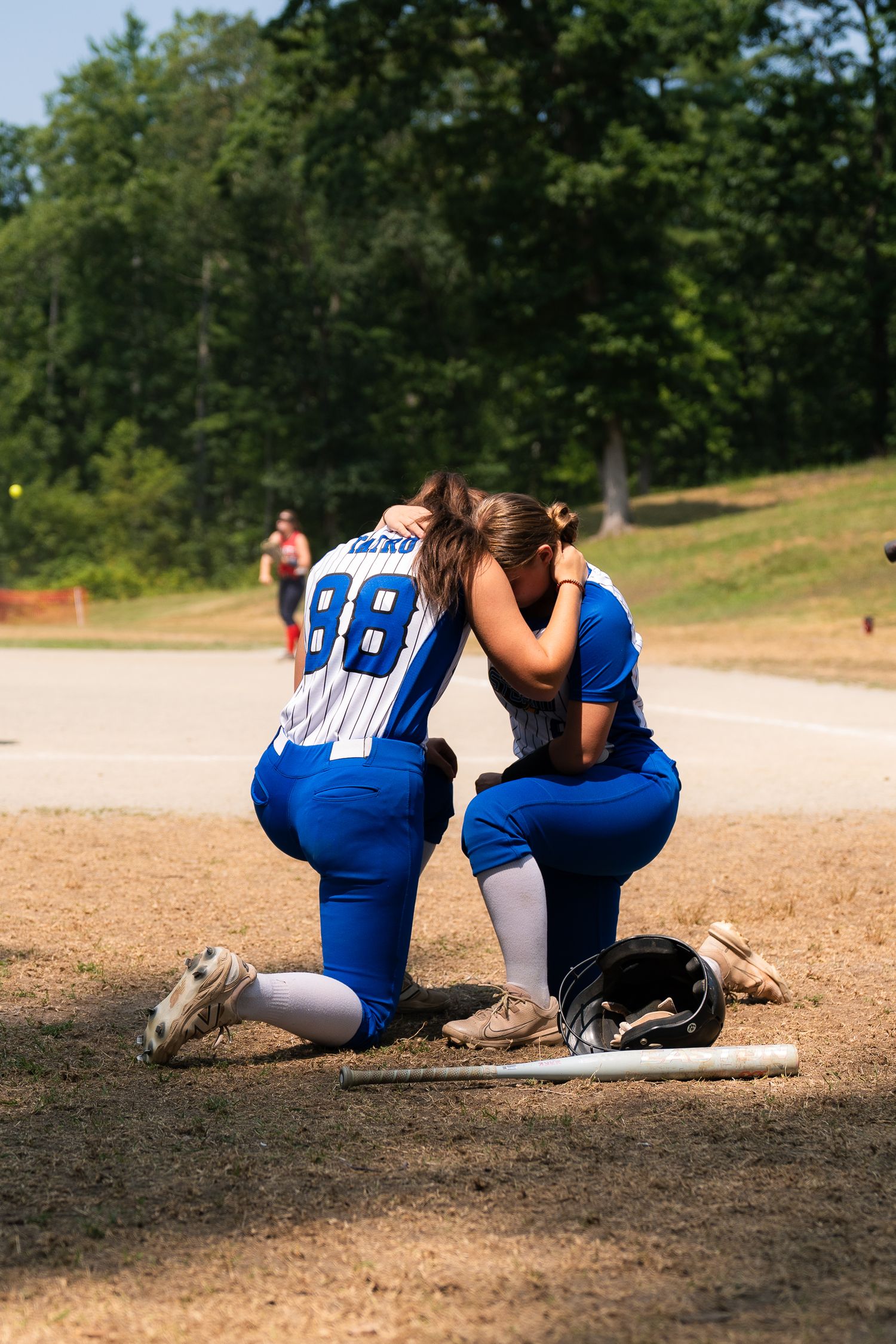 Sequence showing softball player sliding into base on dirt field wearing blue uniform.