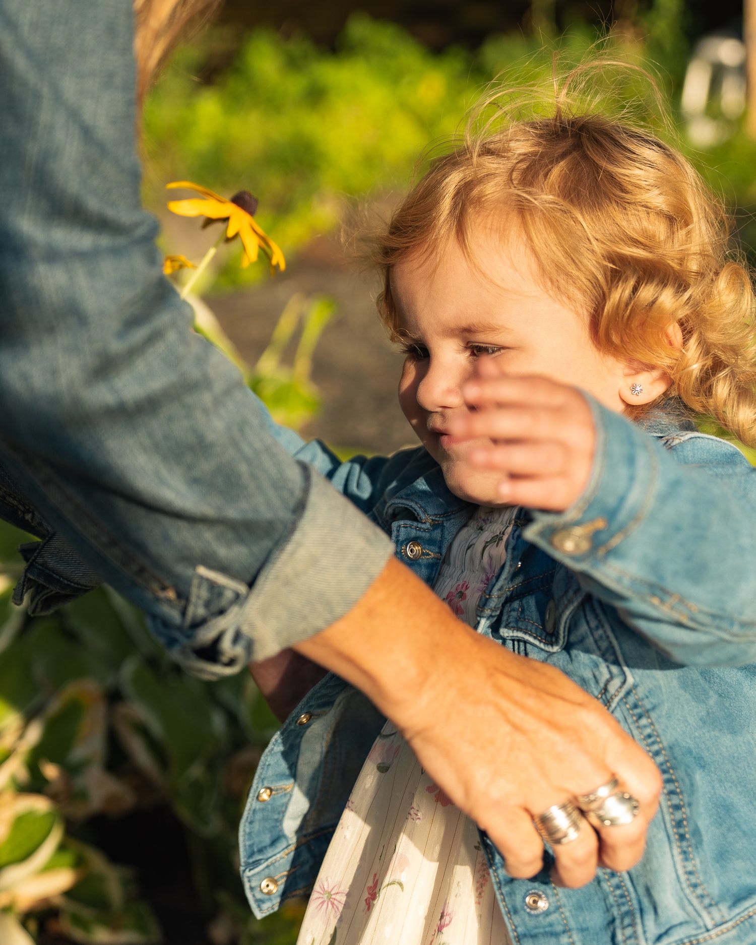 Hand holds up a sun-ripened tomato against a blurry green garden background.