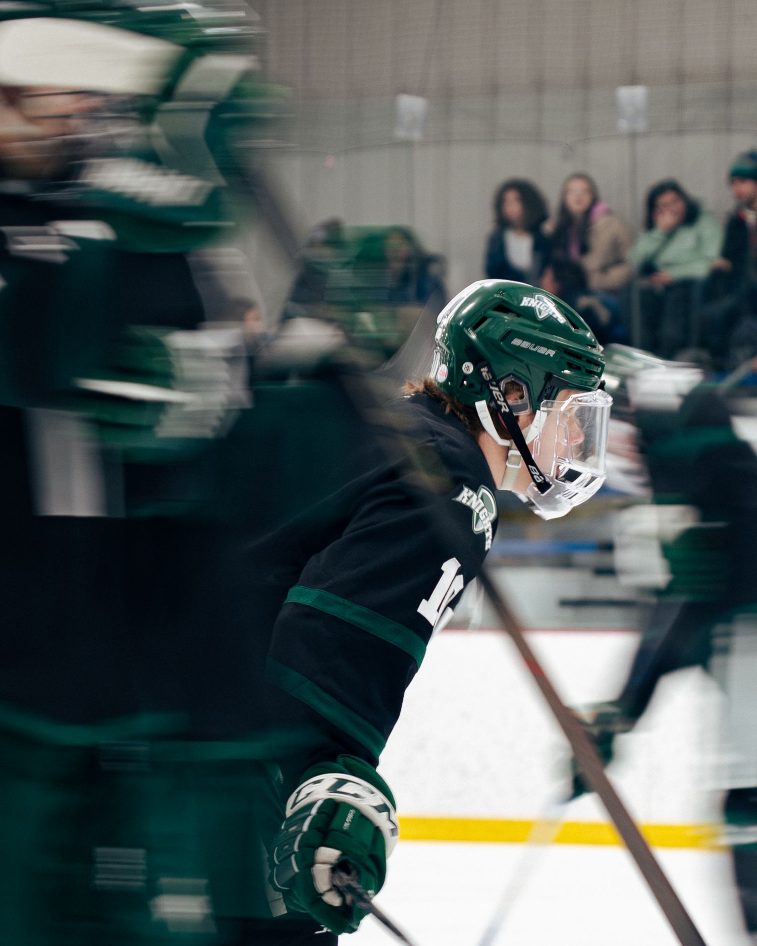 Hockey players in dark jerseys skating in motion during an intense game on the ice rink.