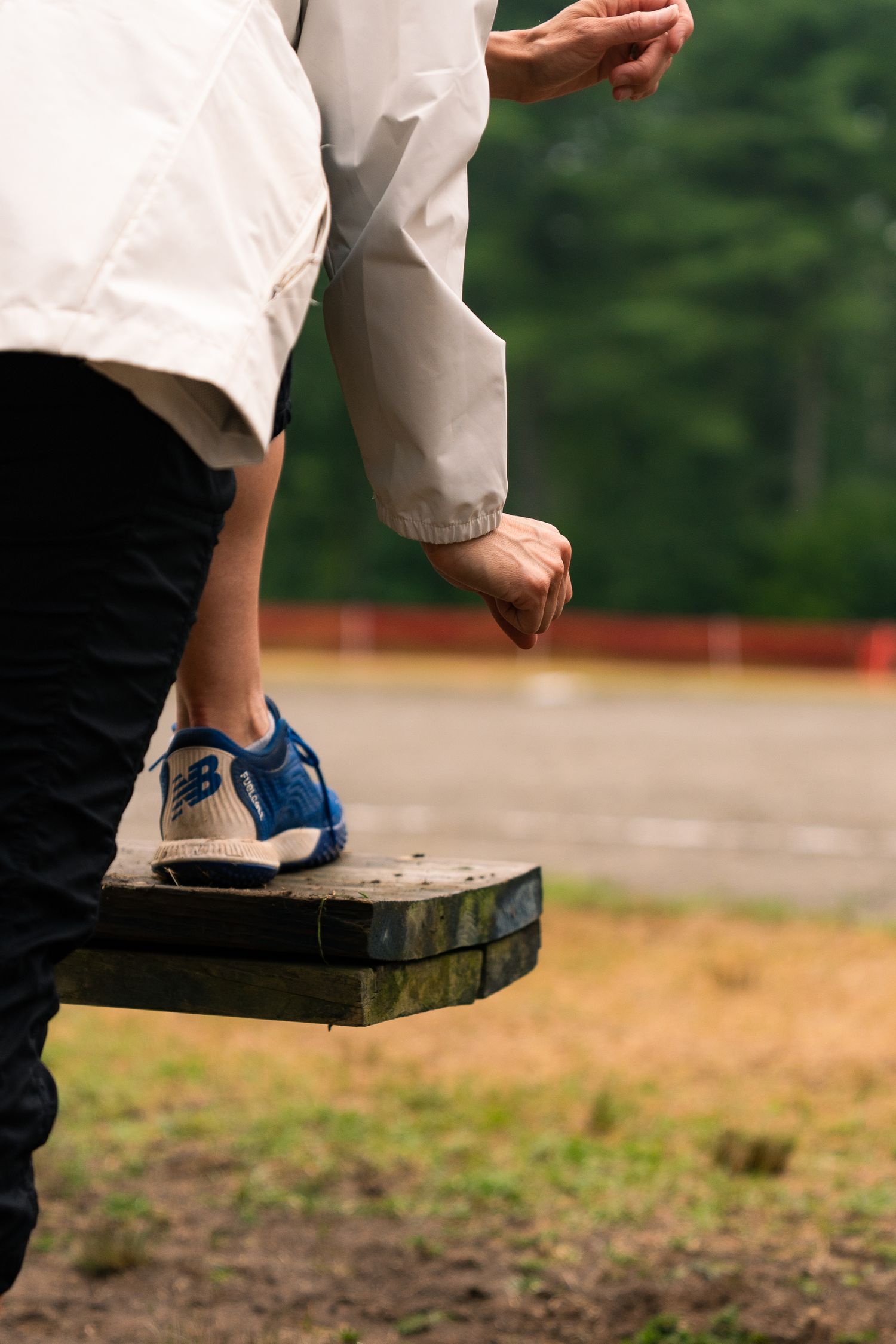 Close-up sequence of feet in blue sneakers stepping onto a wooden platform.
