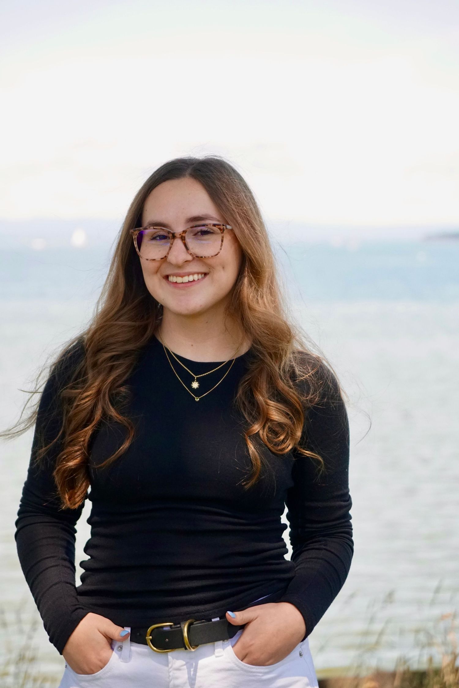 Casual seaside portrait series with black sweater against ocean background.