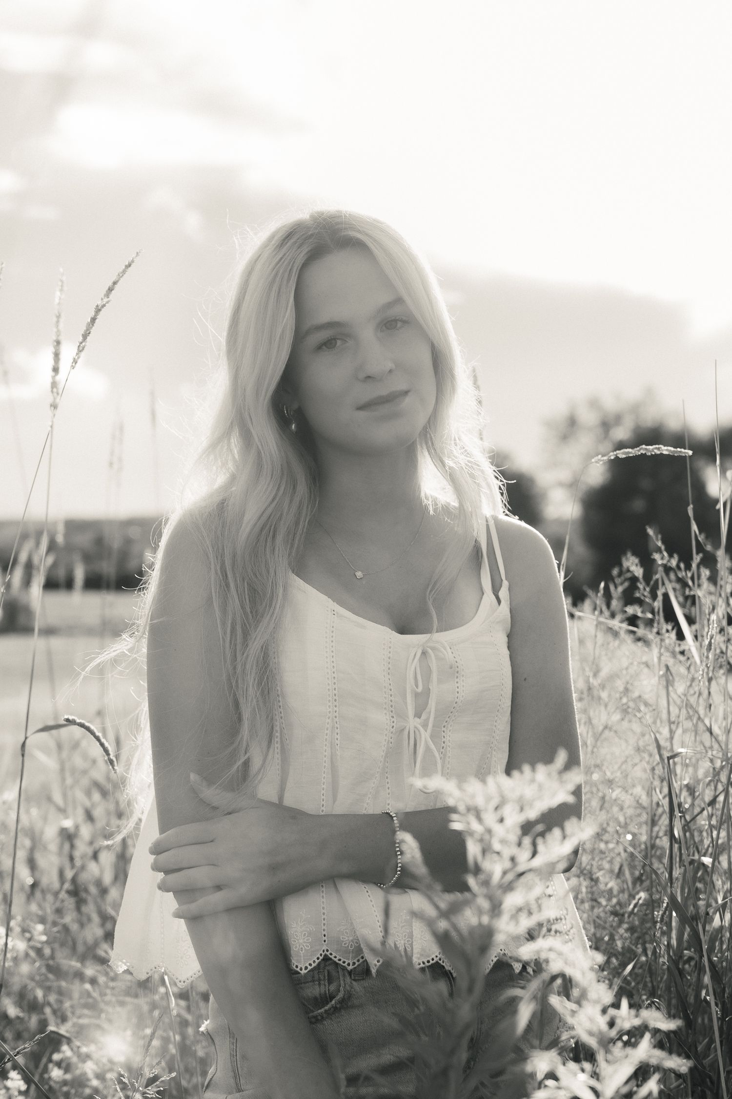 Black and white photo series of someone in a white top sitting in a wildflower meadow on a sunny day.