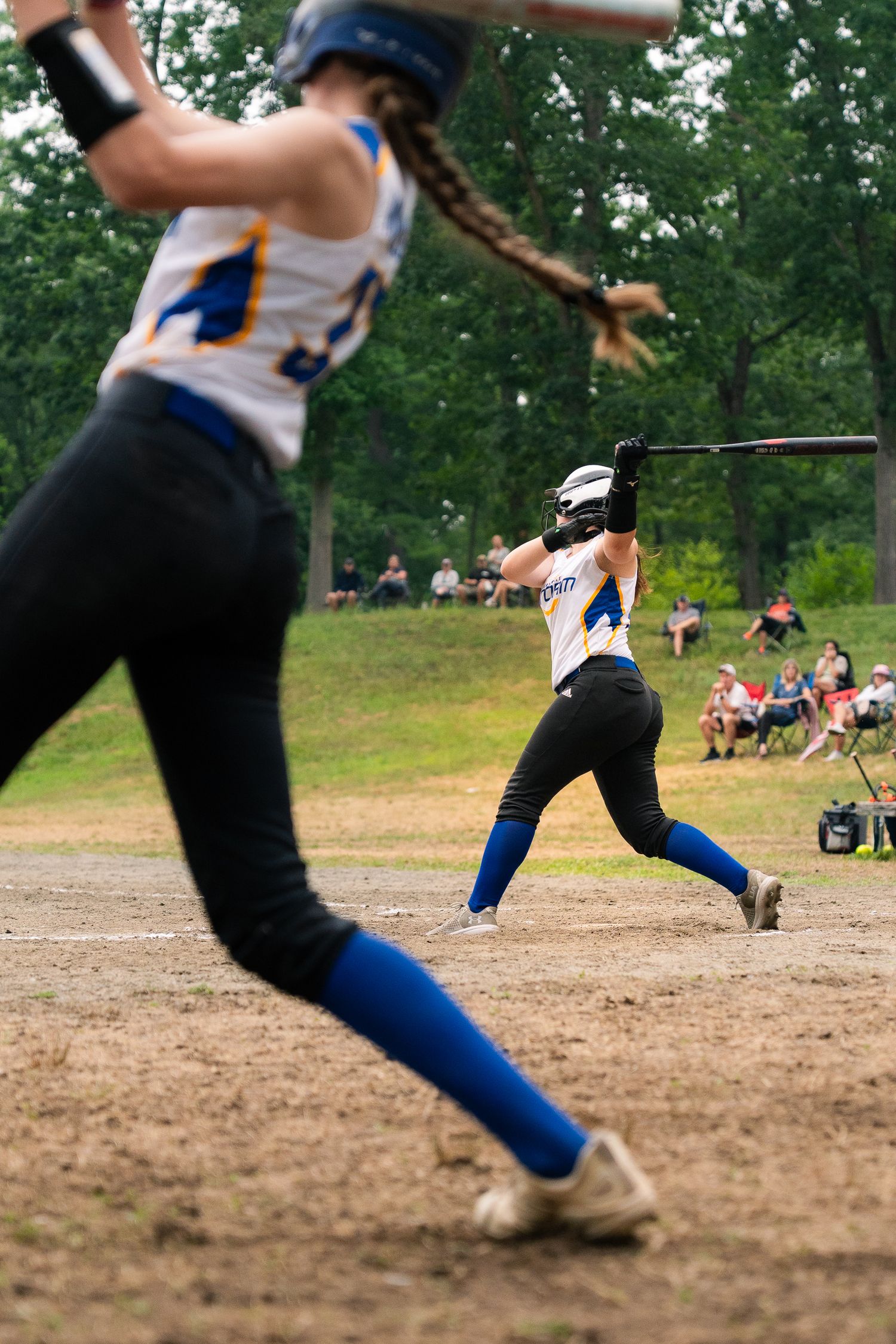 Dynamic sequence of softball players in motion on dirt field wearing blue and white uniforms.