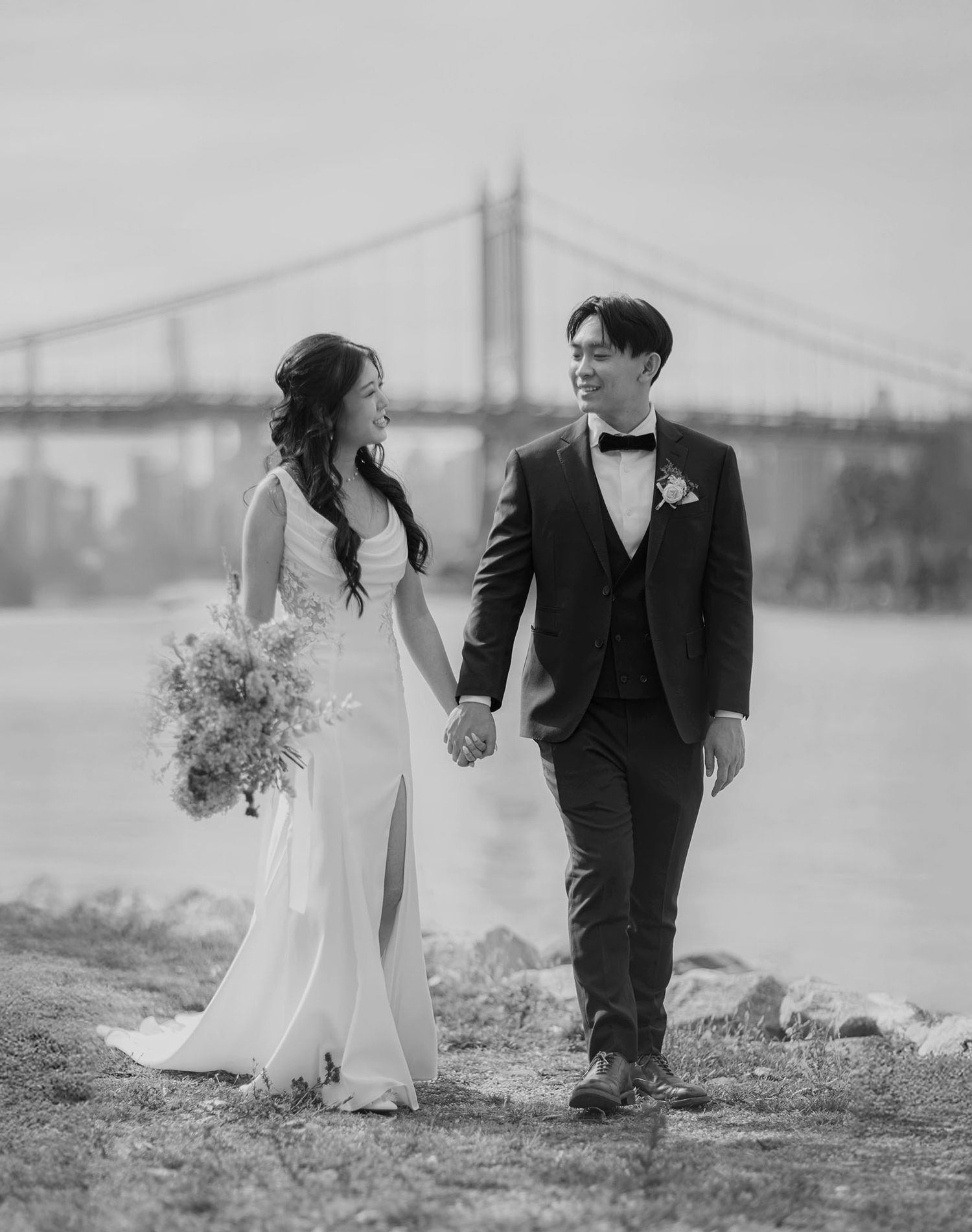 Bride and groom walking along the East River at Astoria Park in Queens NY. Black and white photo.