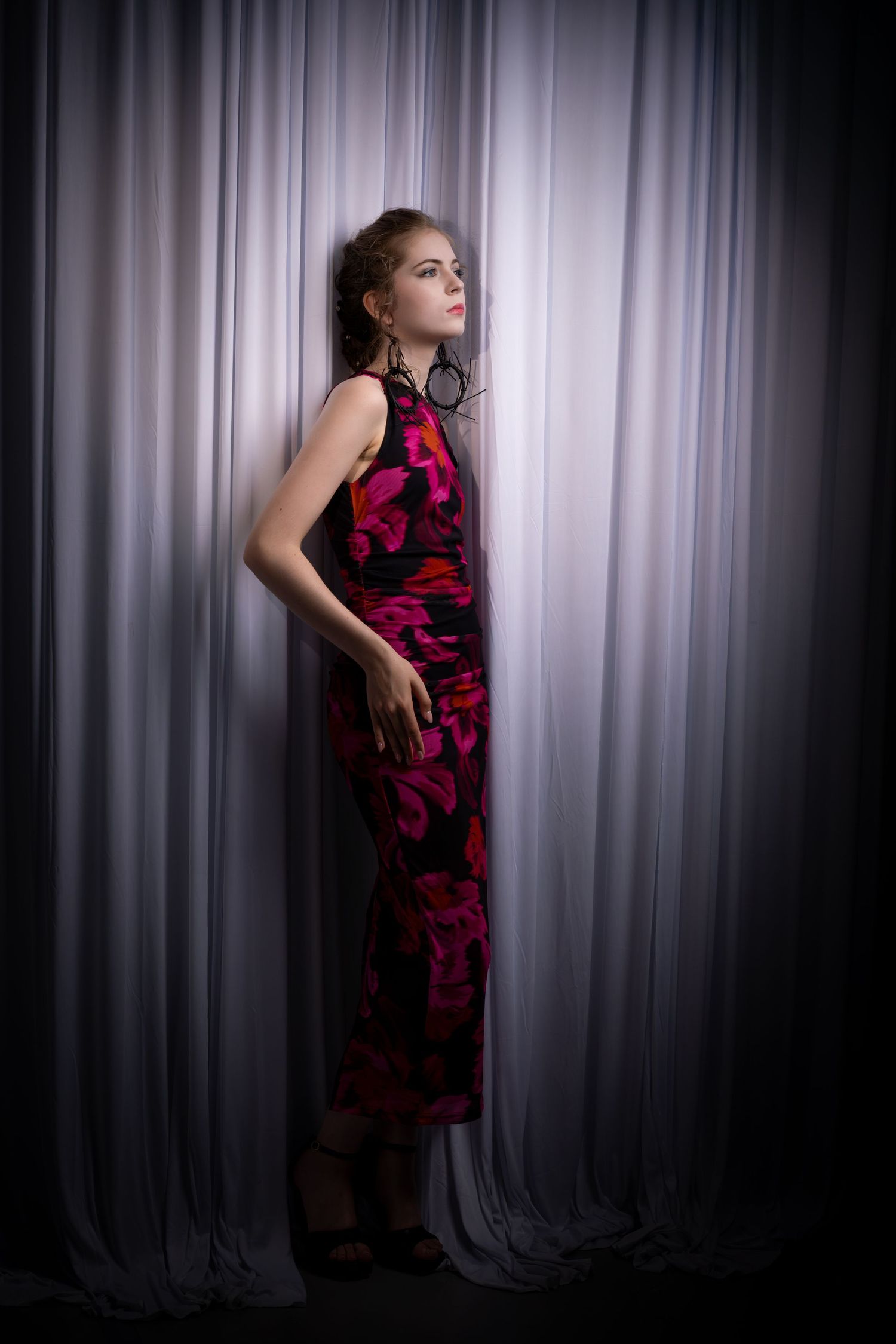 Dramatic silhouette portraits in a red and black patterned dress against white curtains.