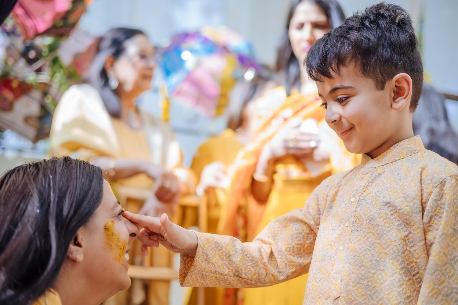 Bride and groom covered in turmeric during an Indo-Norwegian wedding and Family applying Haldi to the bride during a joyful wedding ritual