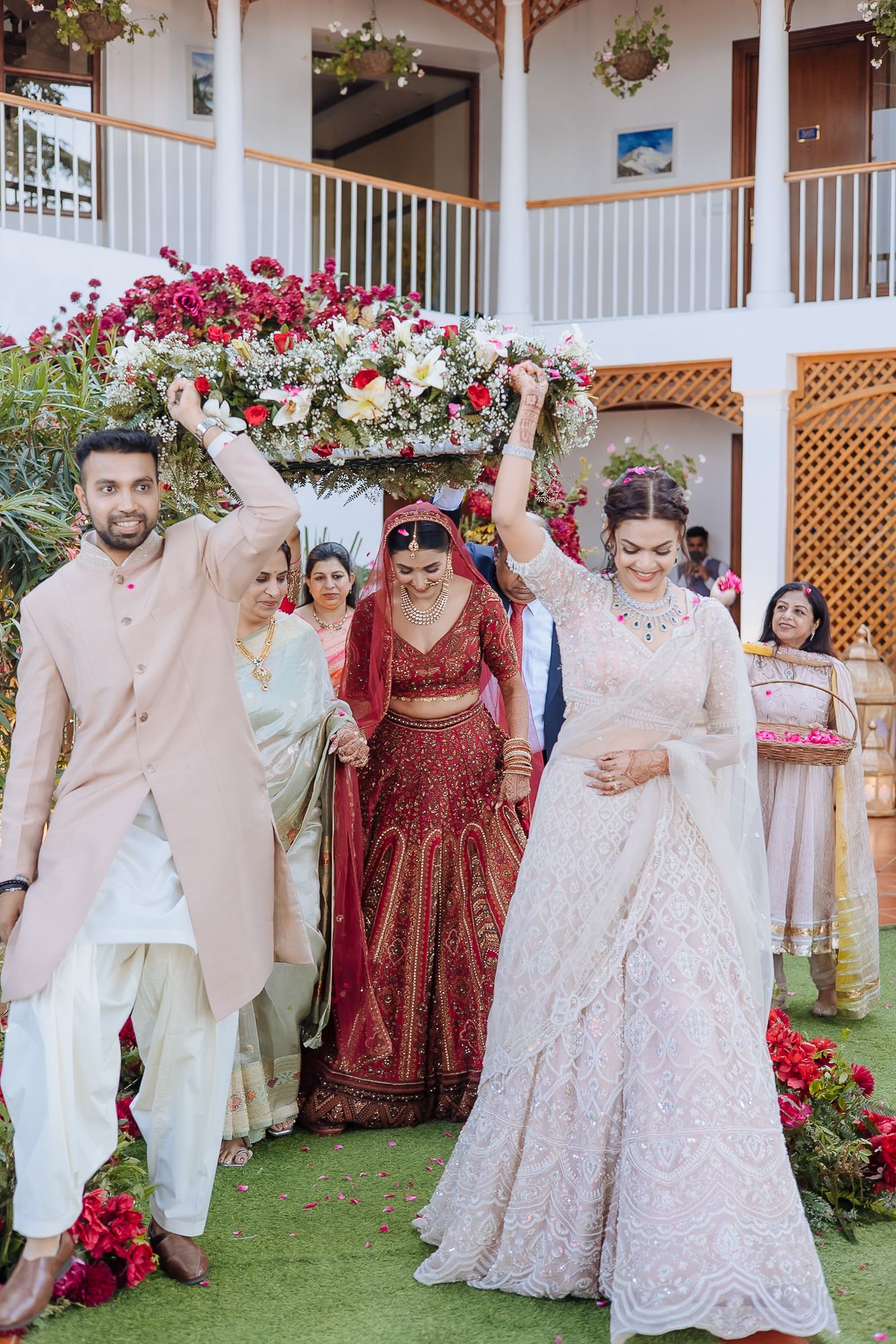 Indian bride in maroon Lehenga and floral entrance at an intimate wedding of 30 people in the hills at Daleside Manor, Kasauli