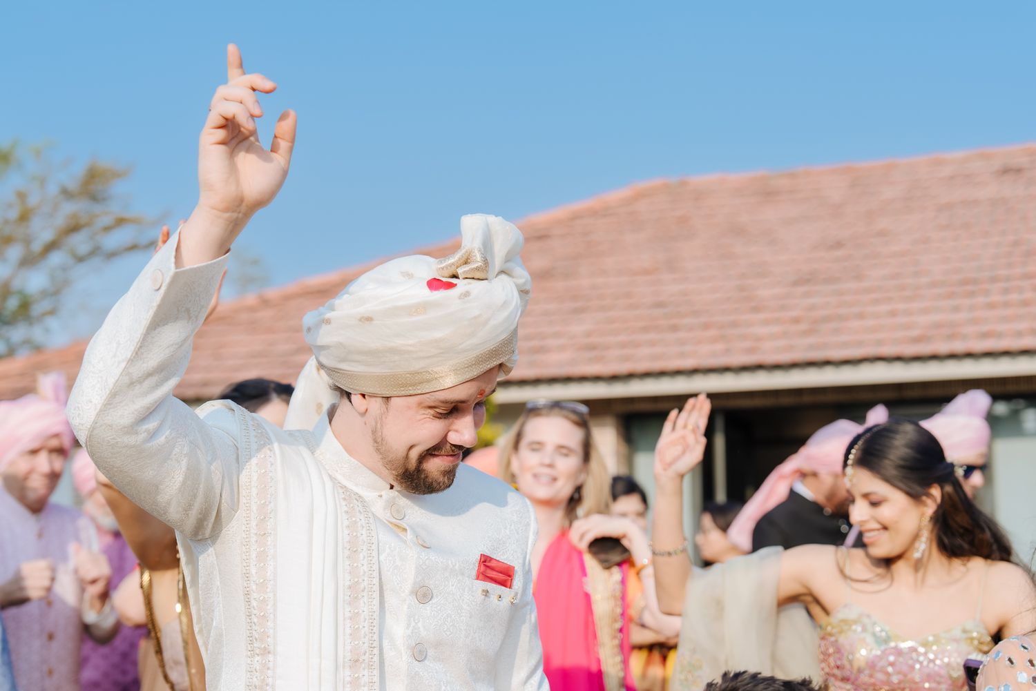 Family celebrating the groom's arrival with music and dancing for an Indo-Norwegian fusion wedding in Forest Hill Chandigarh