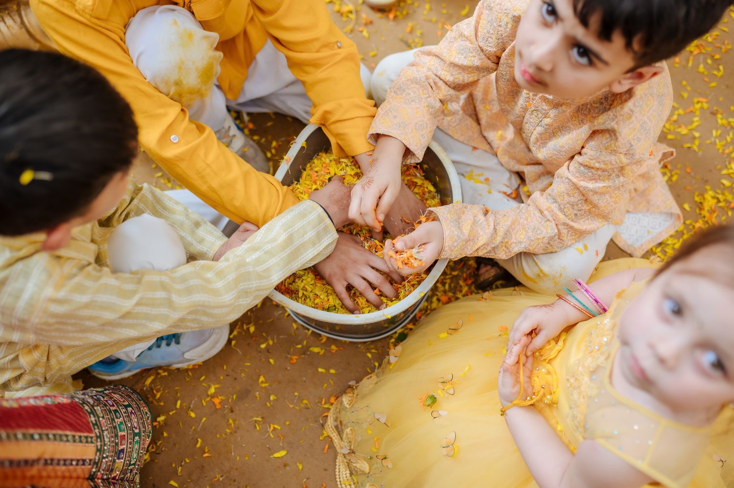 Kids covered in turmeric during an Indo-Norwegian wedding and playing with flowers during a joyful Haldi wedding ritual