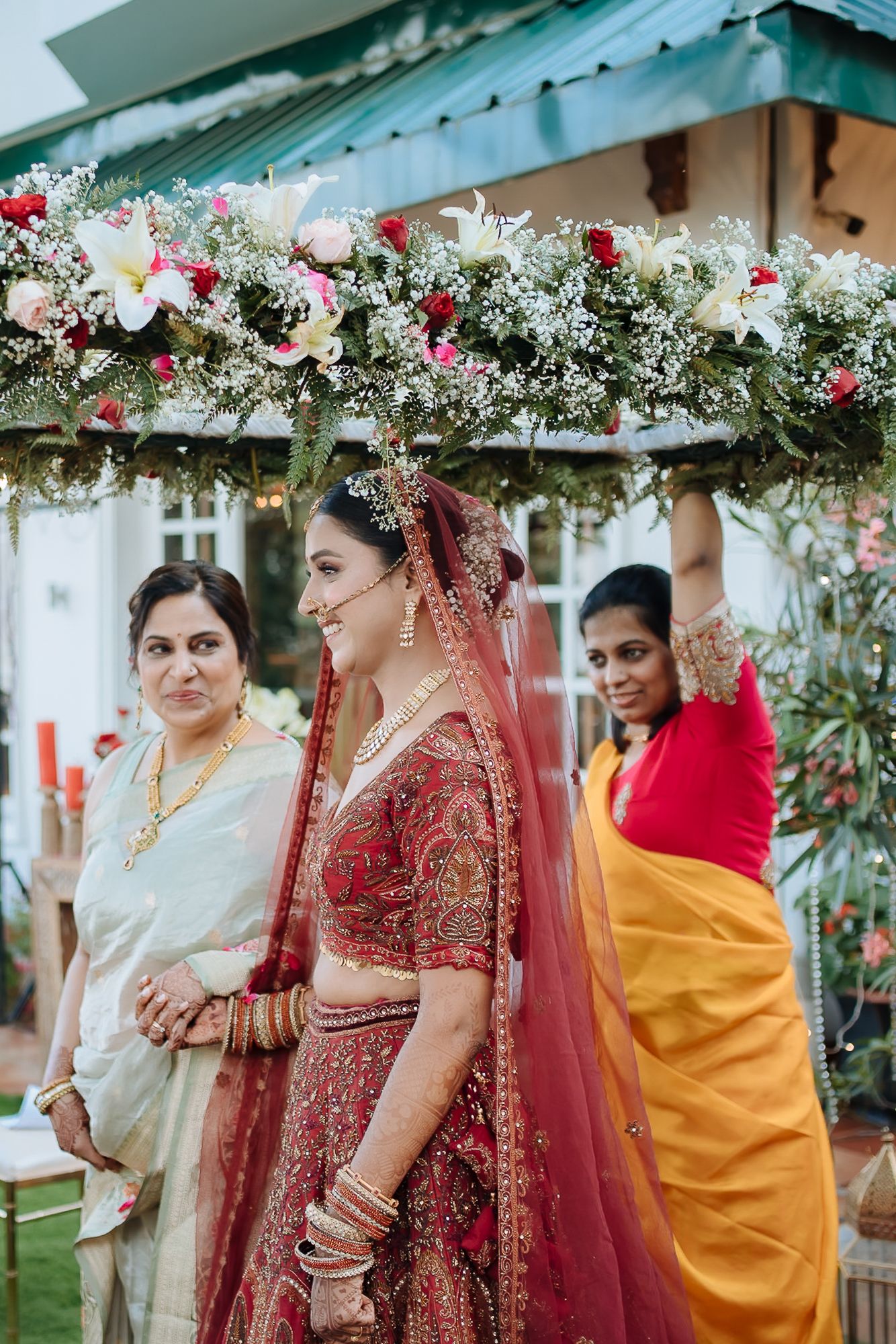 Indian bride in maroon lehenga and floral entrance at an intimate wedding of 30 people in the hills at Daleside Manor, Kasauli