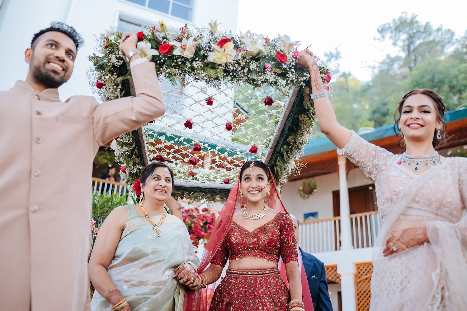 Indian bride in maroon lehenga entering with her family at an intimate wedding of 30 people in the hills at Daleside Manor, Kasauli