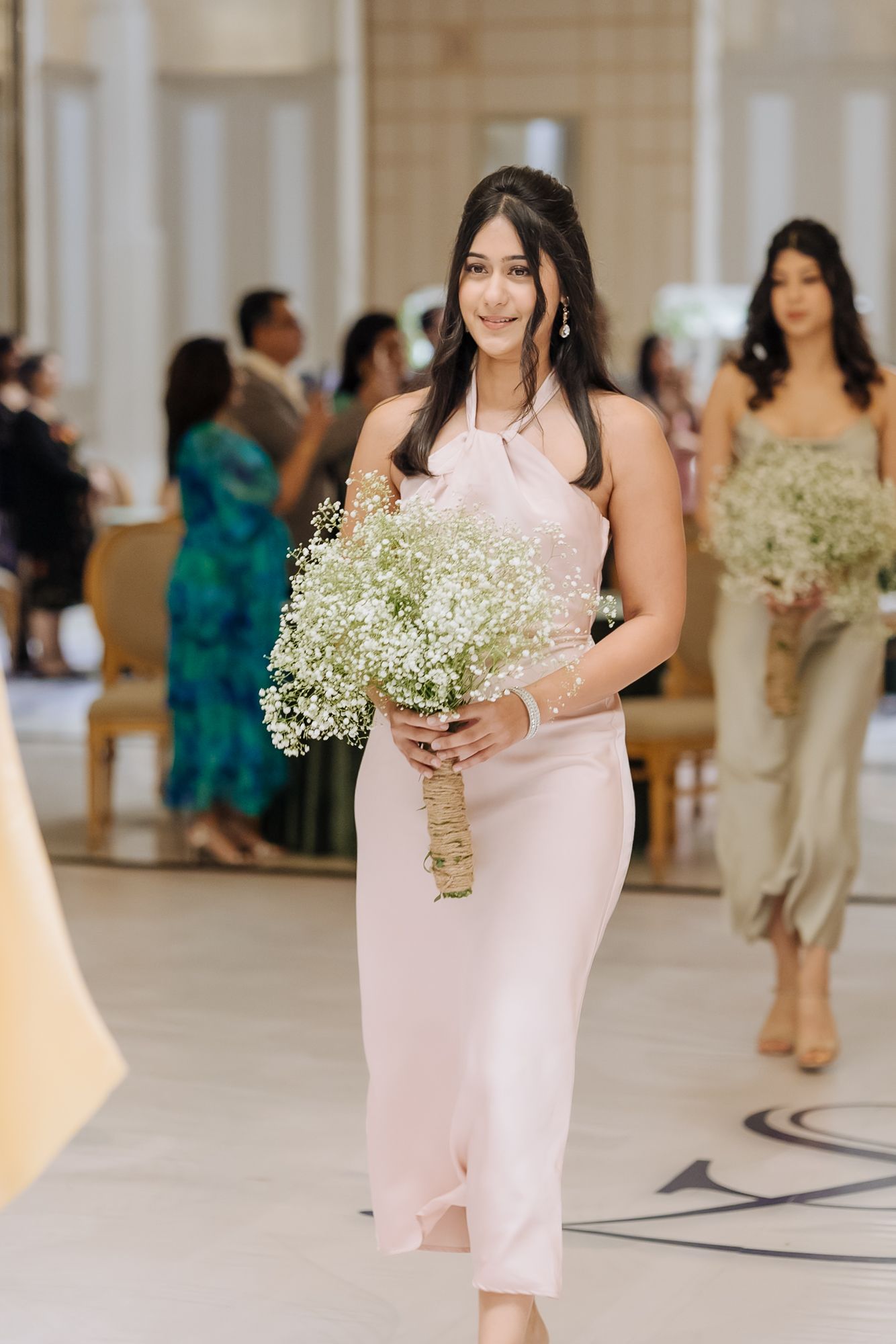 Bridesmaids walking down the aisle during Shorye and Leah's Christian wedding ceremony at Tivoli Chattarpur