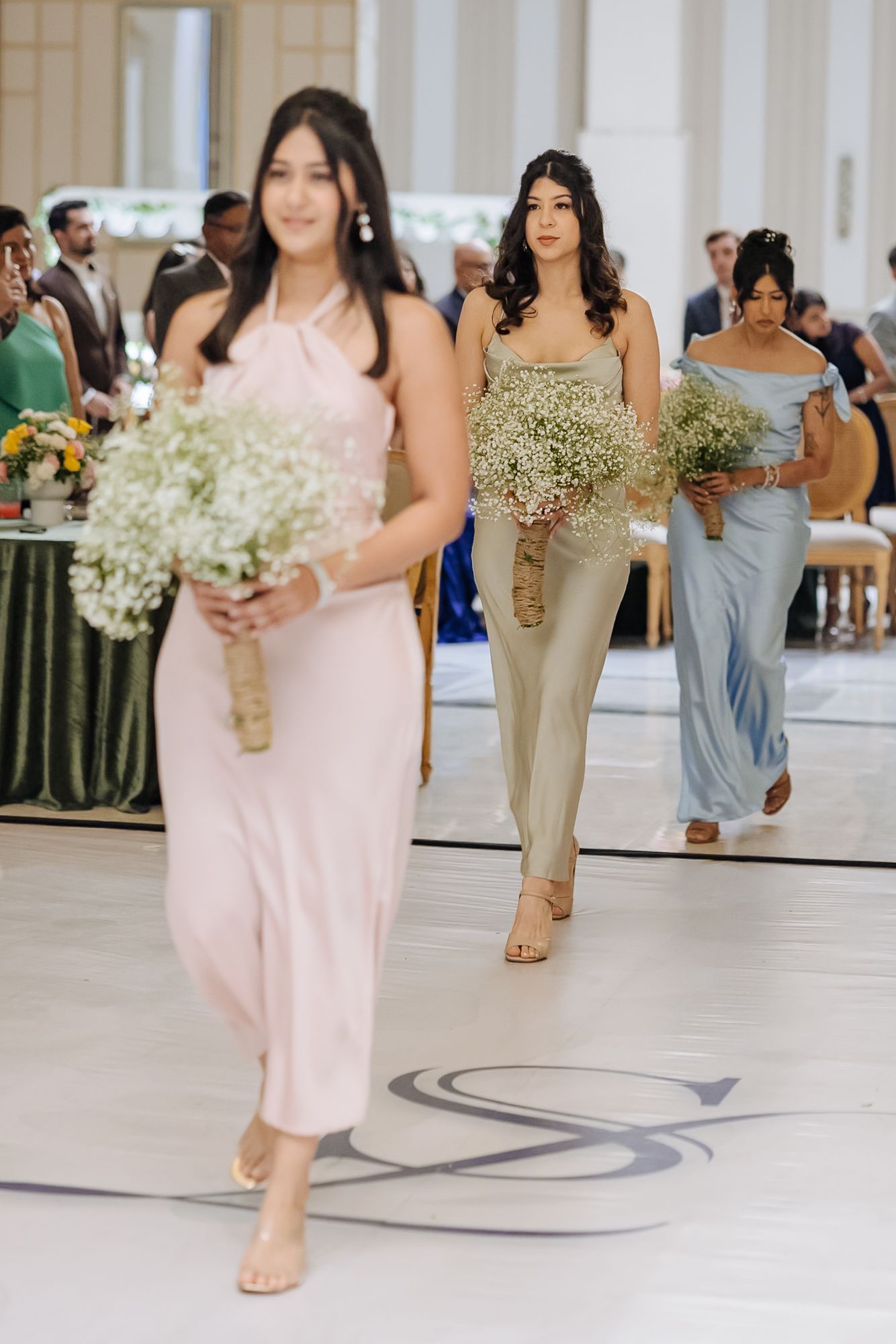 Bridesmaids walking down the aisle during Shorye and Leah's Christian wedding ceremony at Tivoli Chattarpur