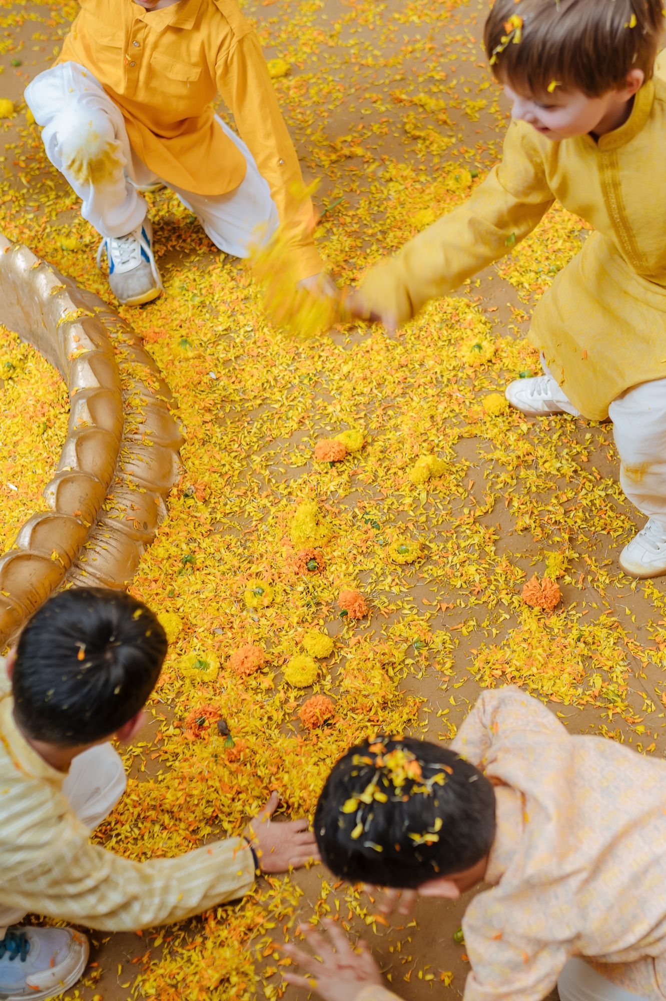 Kids covered in turmeric during an Indo-Norwegian wedding and playing with flowers during a joyful Haldi wedding ritual