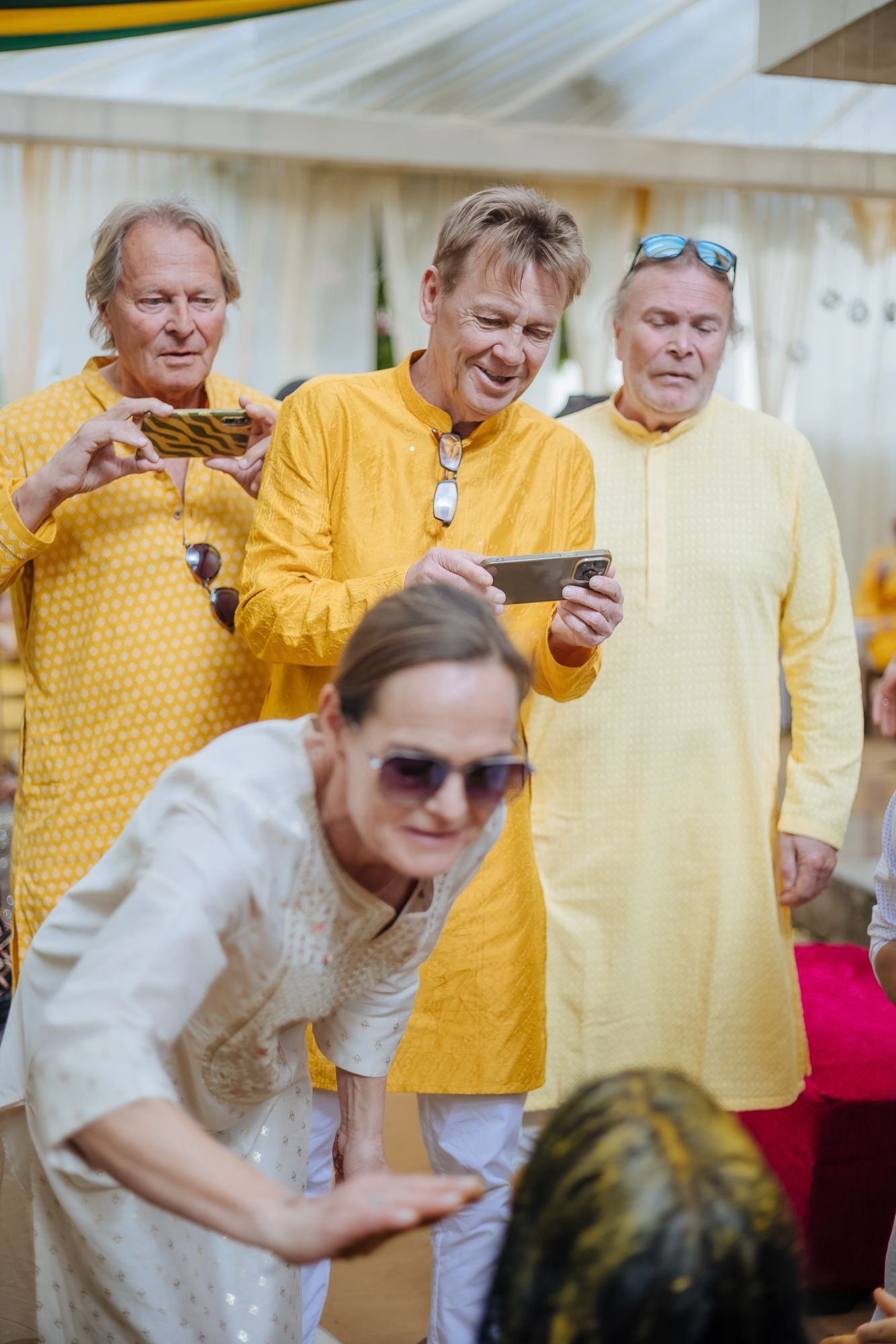 Bride and groom covered in turmeric during an Indo-Norwegian wedding and Family applying Haldi to the bride during a joyful wedding ritual