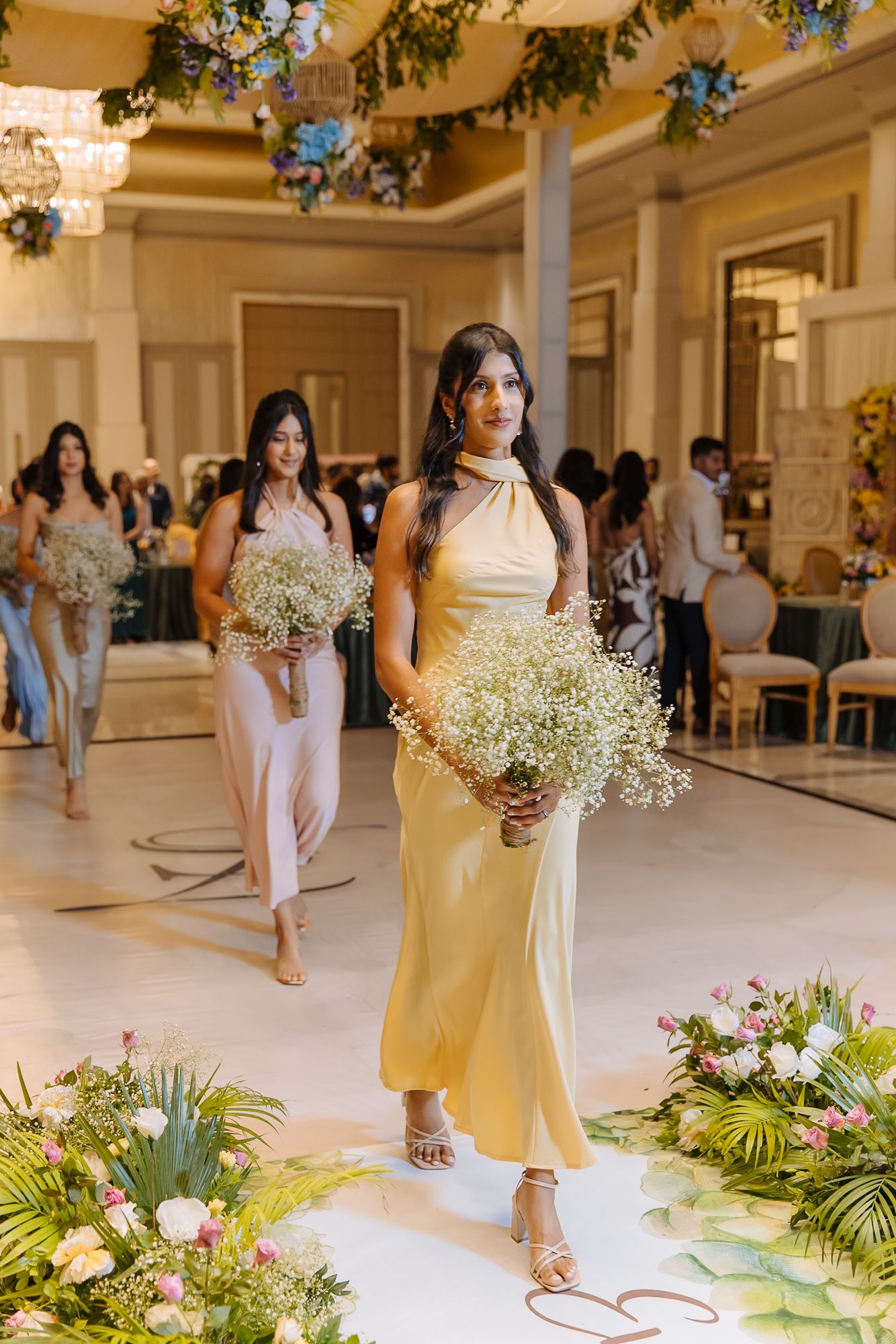 Bridesmaids walking down the aisle during Shorye and Leah's Christian wedding ceremony at Tivoli Chattarpur