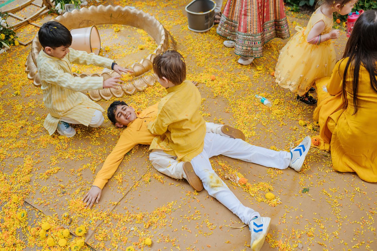 Kids covered in turmeric during an Indo-Norwegian wedding and playing with flowers during a joyful Haldi wedding ritual