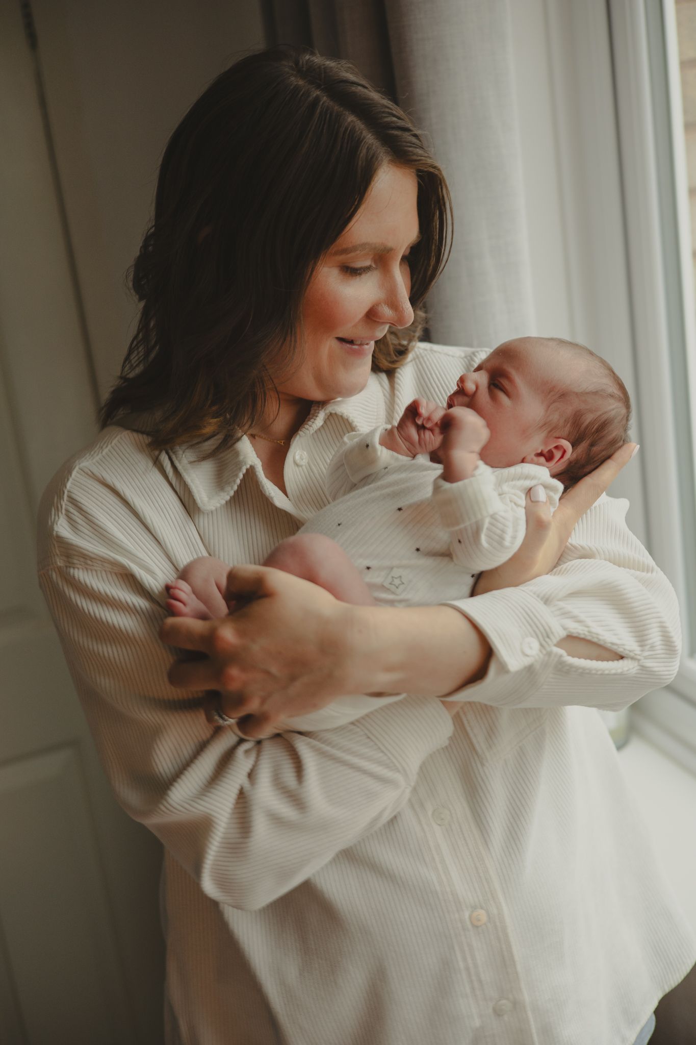 A newborn baby in their mothers arms smiling down, in Telford, Shropshire.