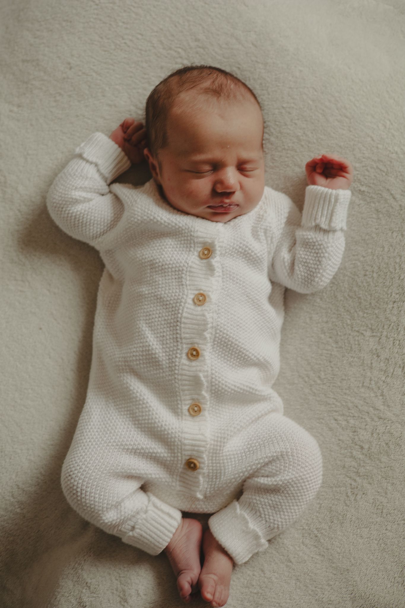 Photo of a newborn baby in white knitted romper during newborn photography session in Telford.