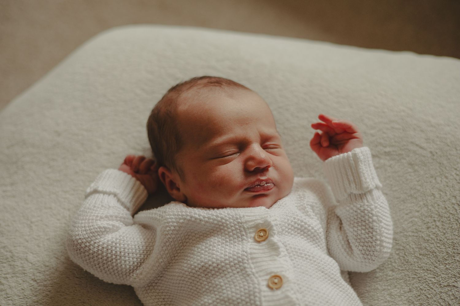 Photo of a newborn baby in white knitted romper during newborn photography session in Telford.