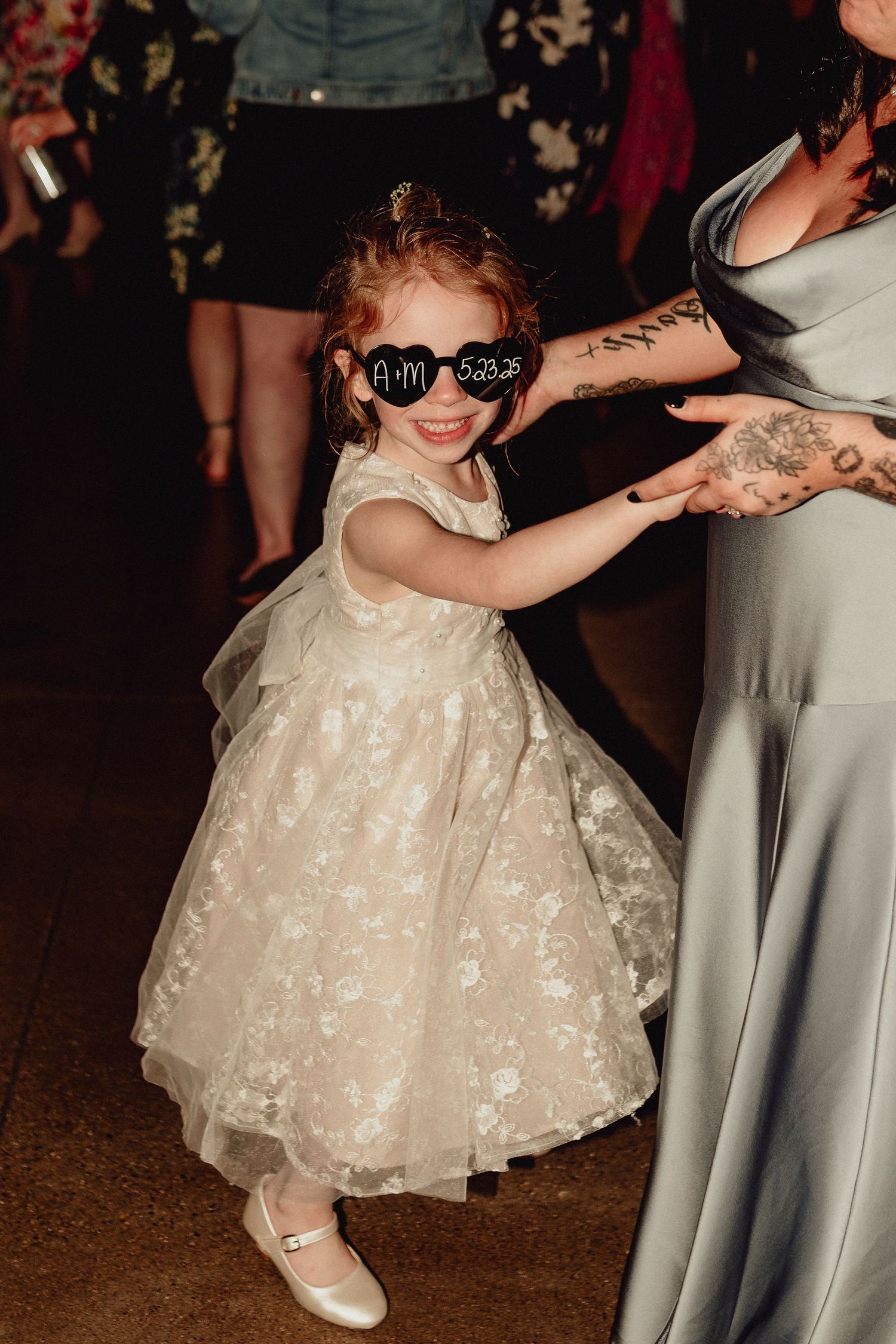 A sequence of photos showing a little girl in a white lace dress dancing at a wedding reception.