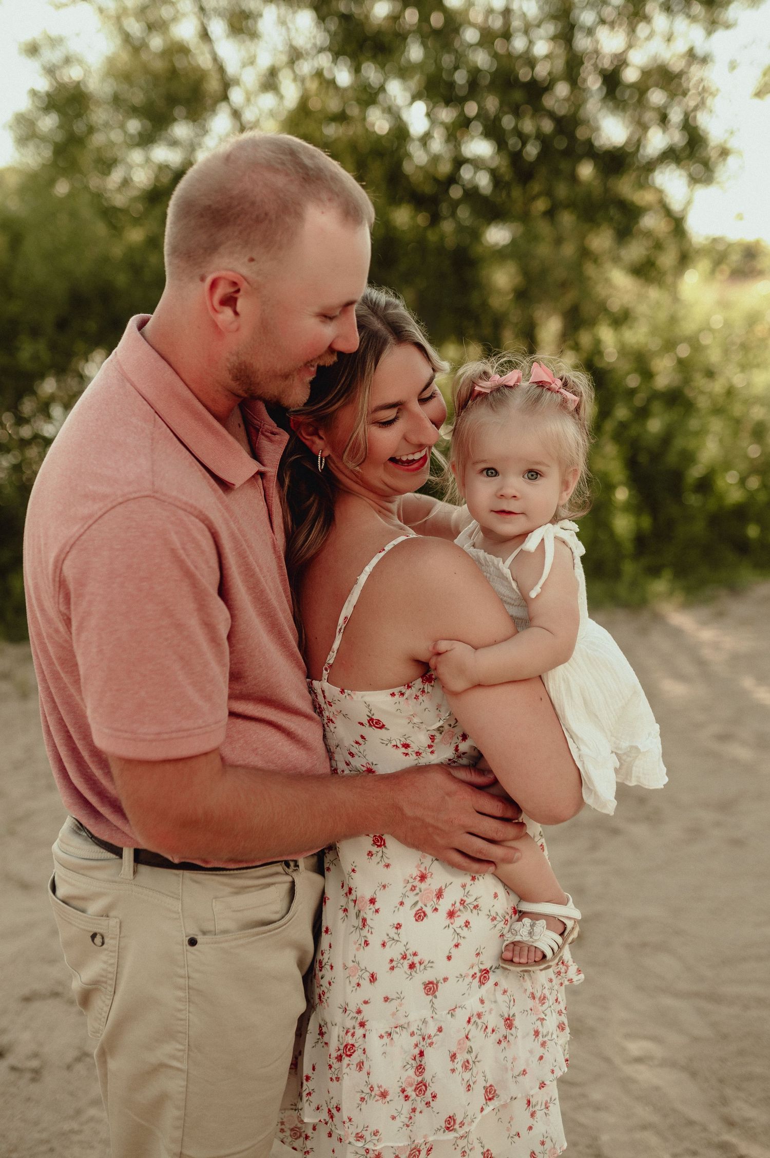 Family embracing on beach during golden hour sunset photoshoot.