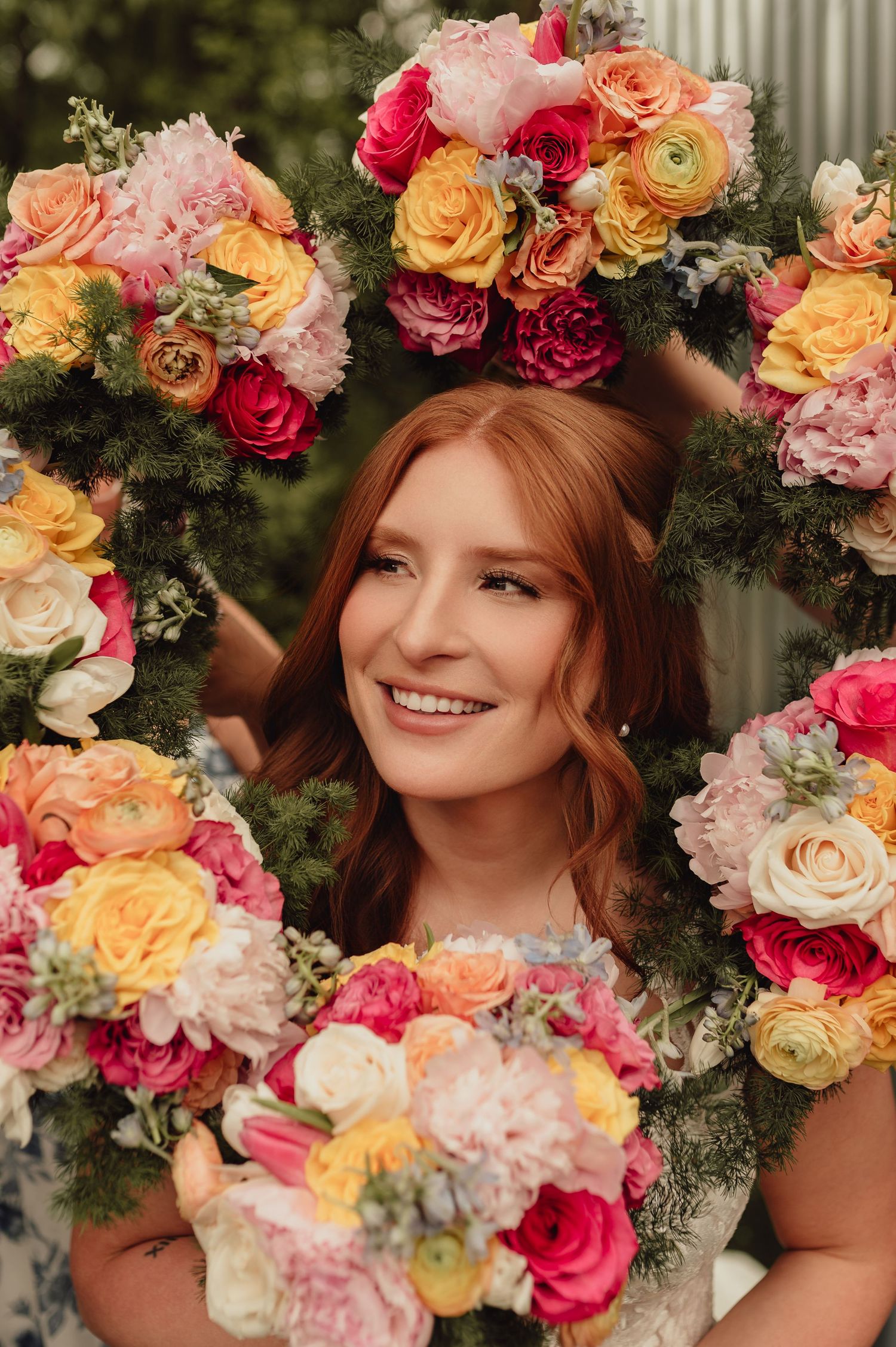 Vibrant floral wreath with pink, peach and yellow roses arranged with greenery creates a romantic garden aesthetic.