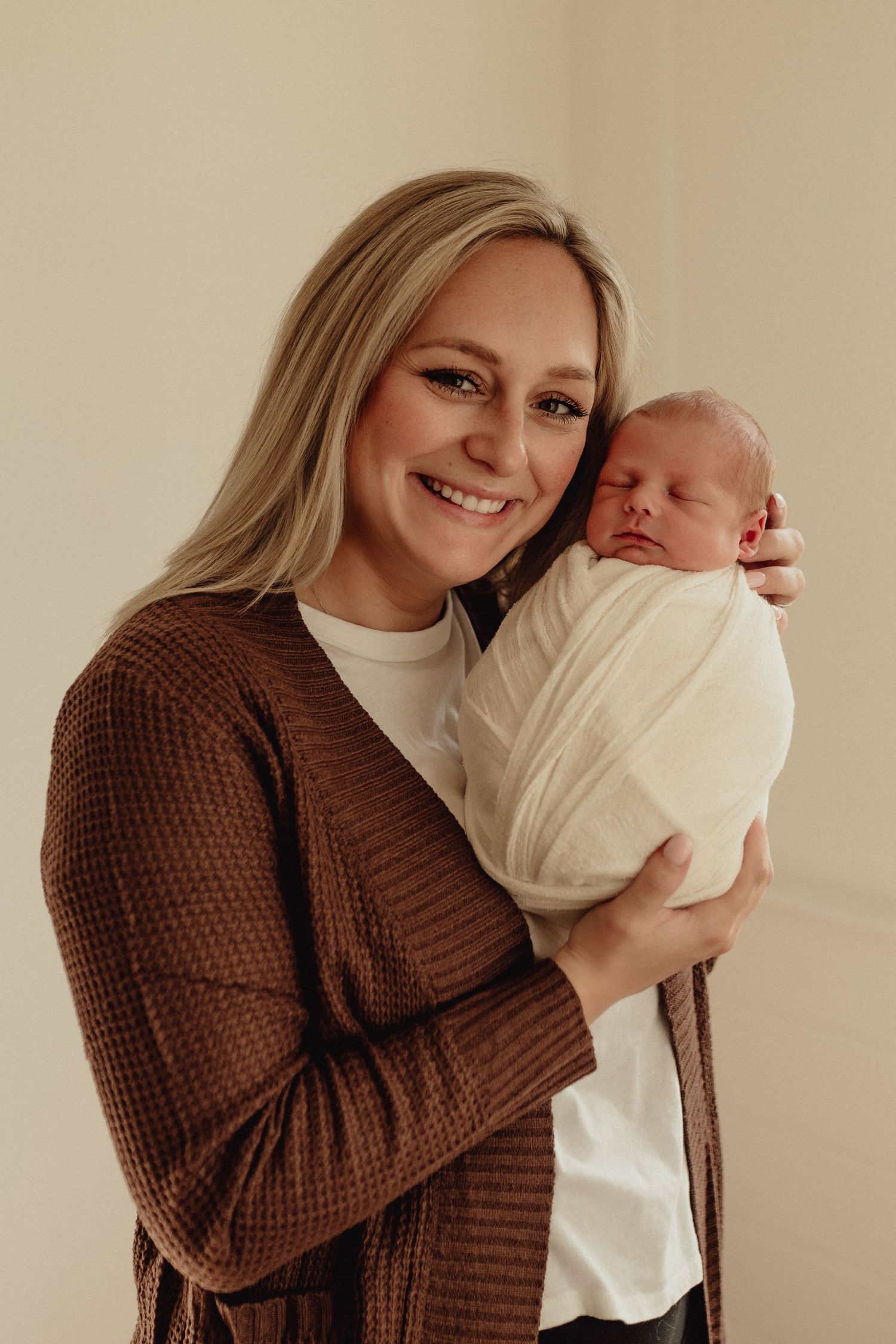 Tender moment between parent and swaddled newborn in warm indoor setting.