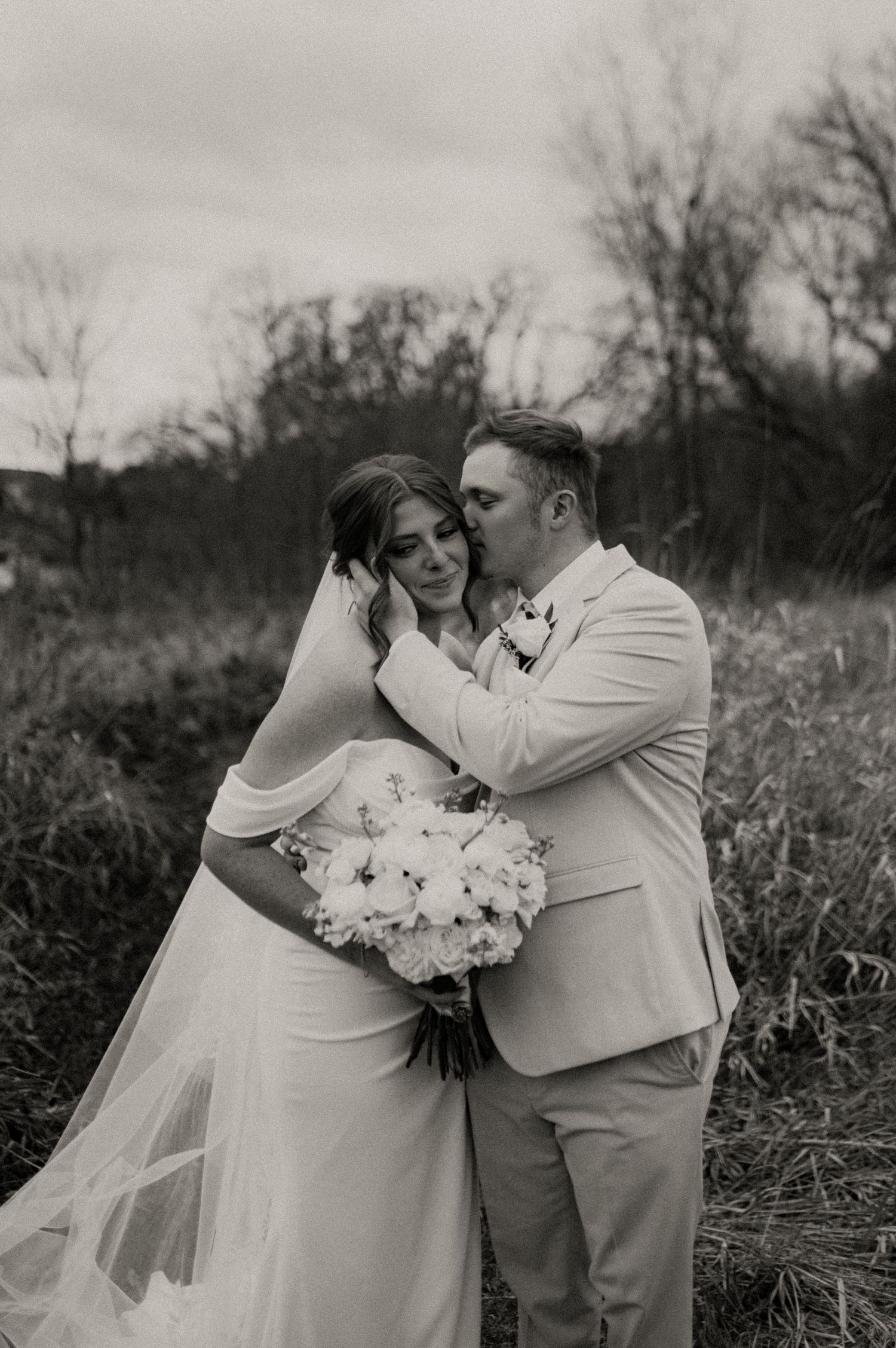 A romantic black and white wedding photo series showing tender moments between newlyweds in a rustic outdoor setting.