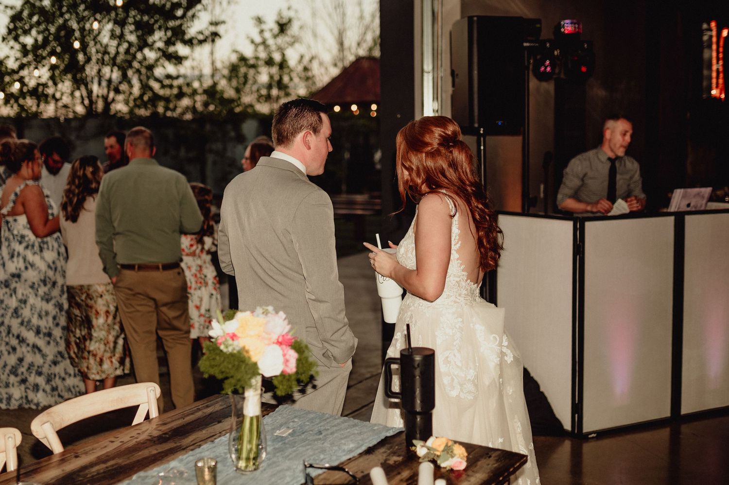 Wedding reception guests mingle and dine at elegant tables in a dimly lit restaurant venue during evening celebration.