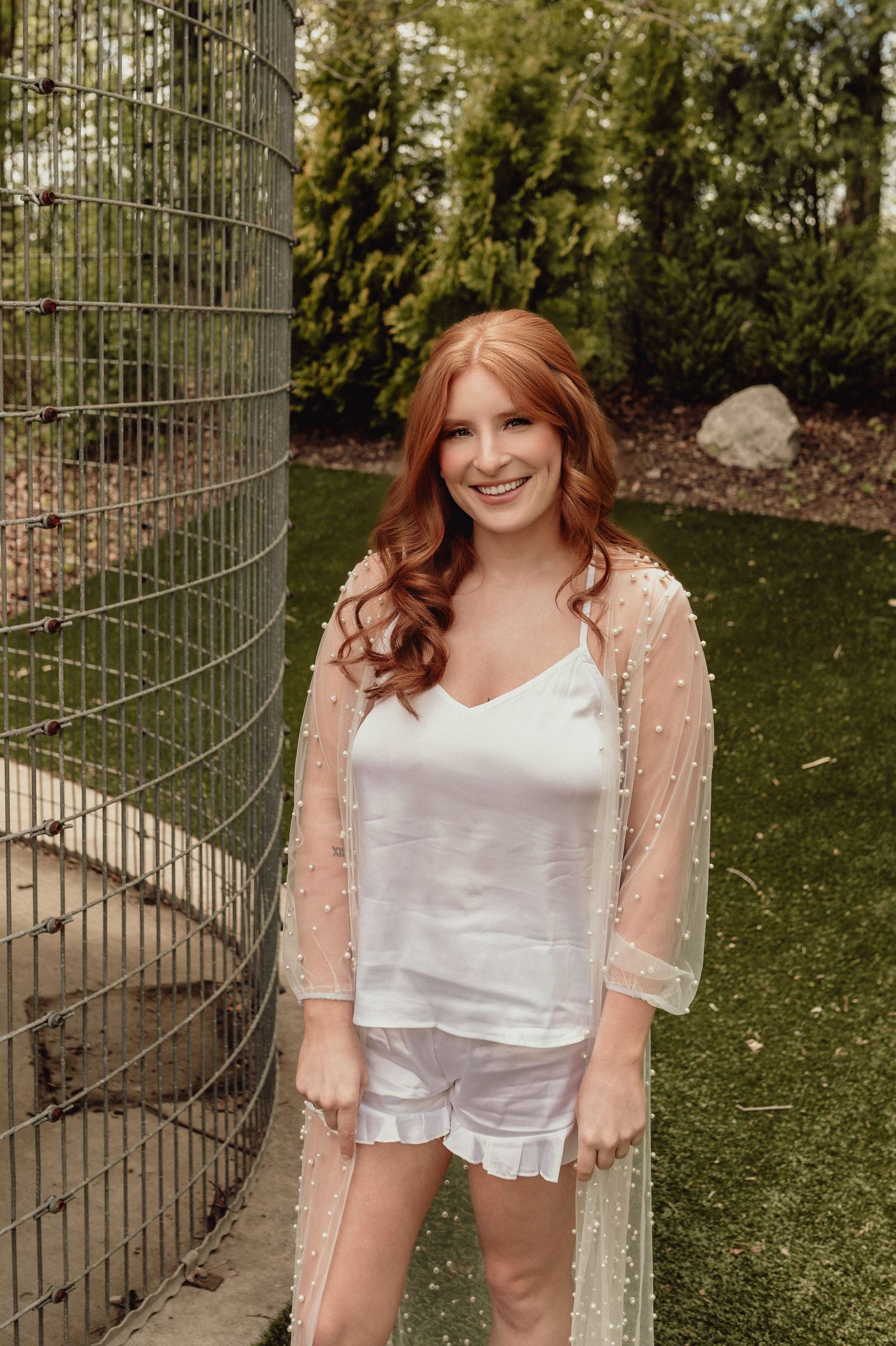 A set of four outdoor photos showing someone wearing a white outfit and peach-colored sheer overlay against a garden backdrop.