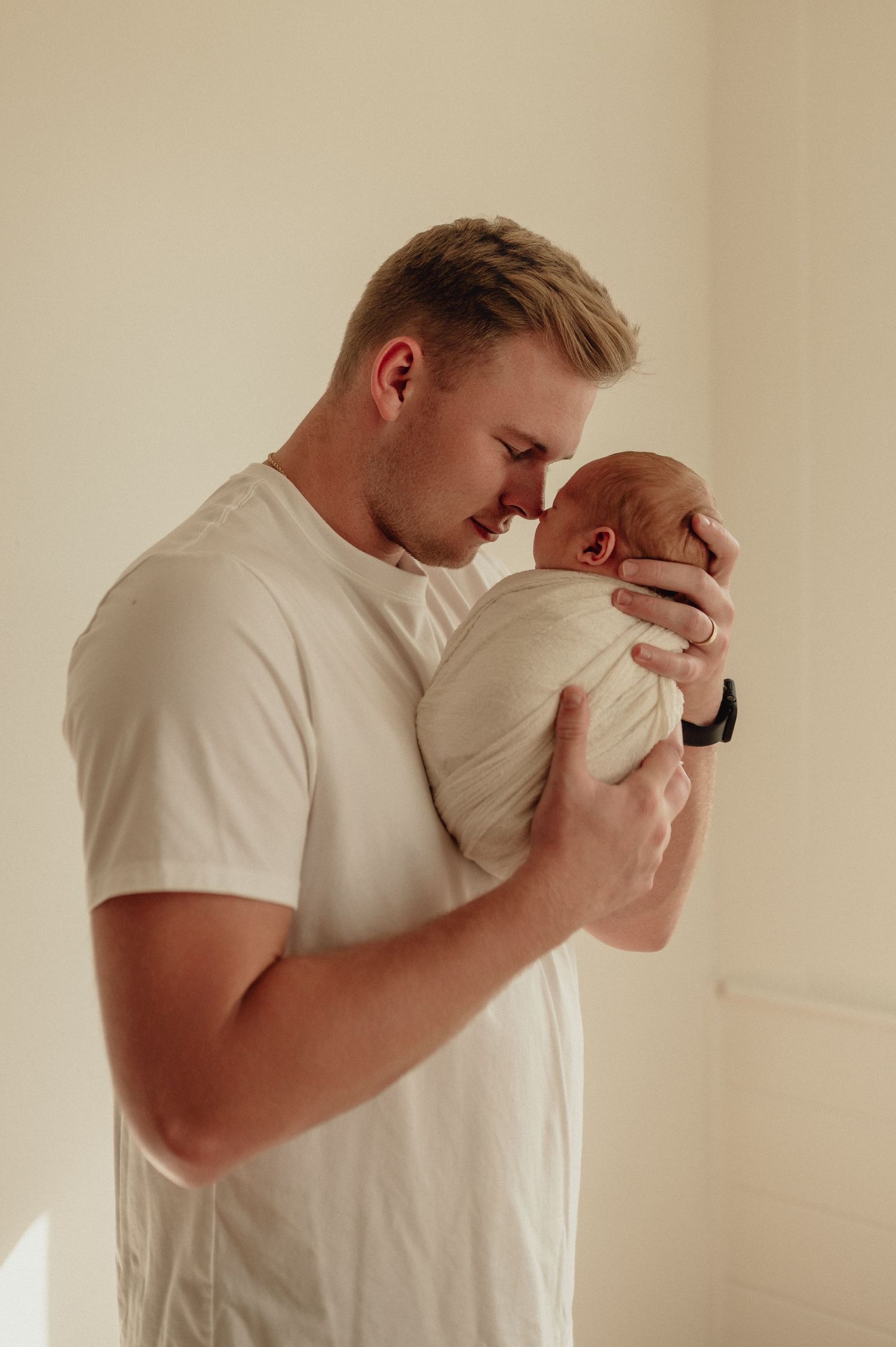 Tender moments captured between two people in white shirts against a neutral background.