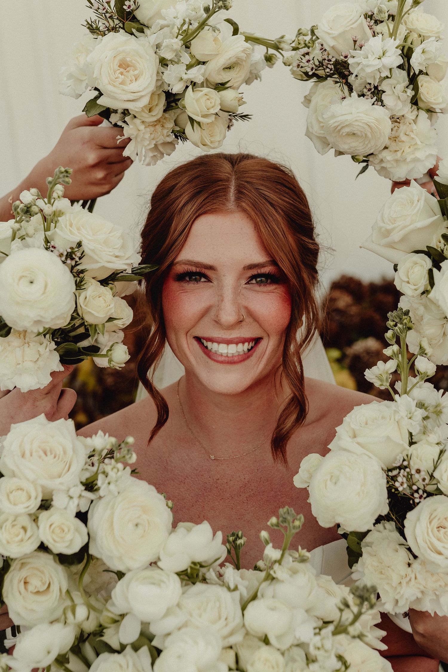 A series of three photos showing someone surrounded by beautiful white roses and floral arrangements at a wedding.