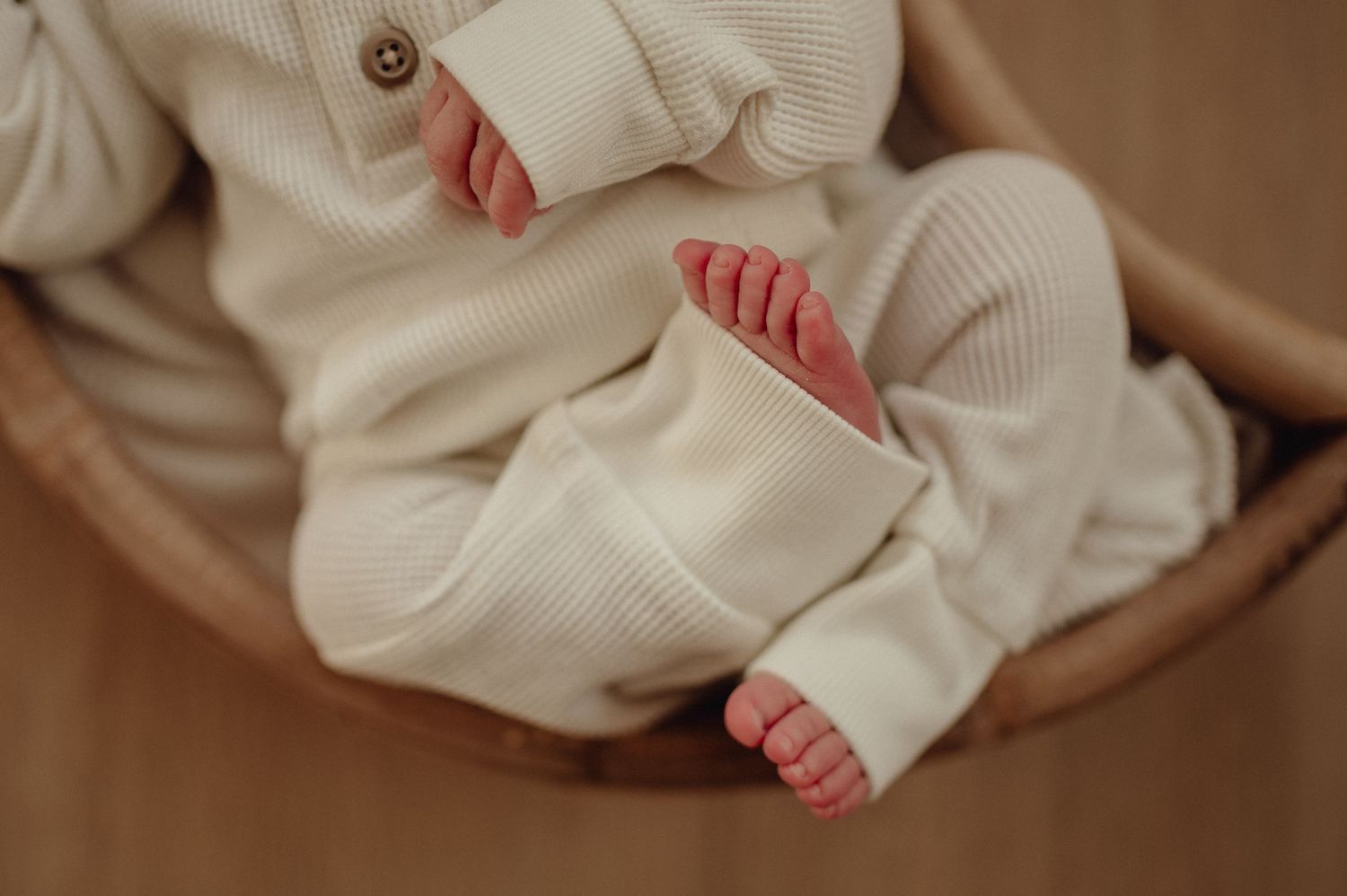 Close up of sleeping newborn wearing cozy cream colored sweater.