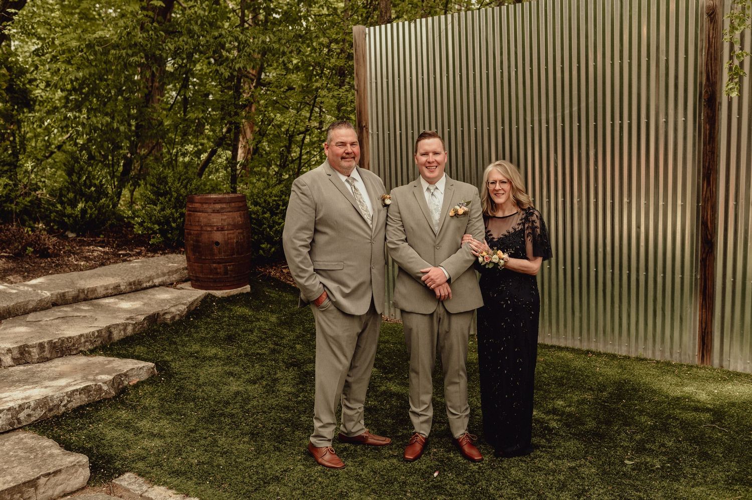 A group stands together outdoors in front of a corrugated metal wall during a casual gathering.