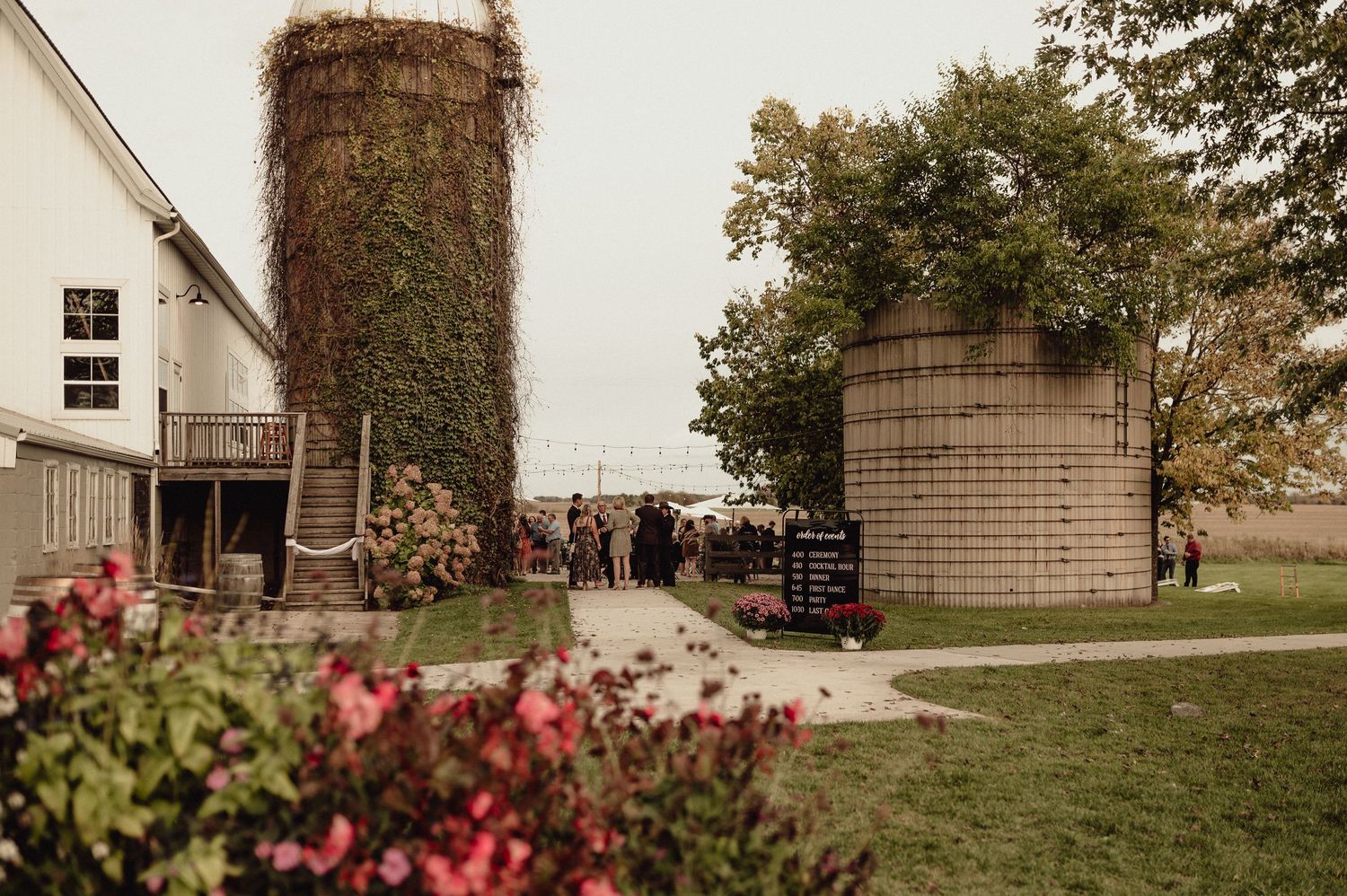 Exterior view of a rustic wedding venue with brick walls and blooming flowers.